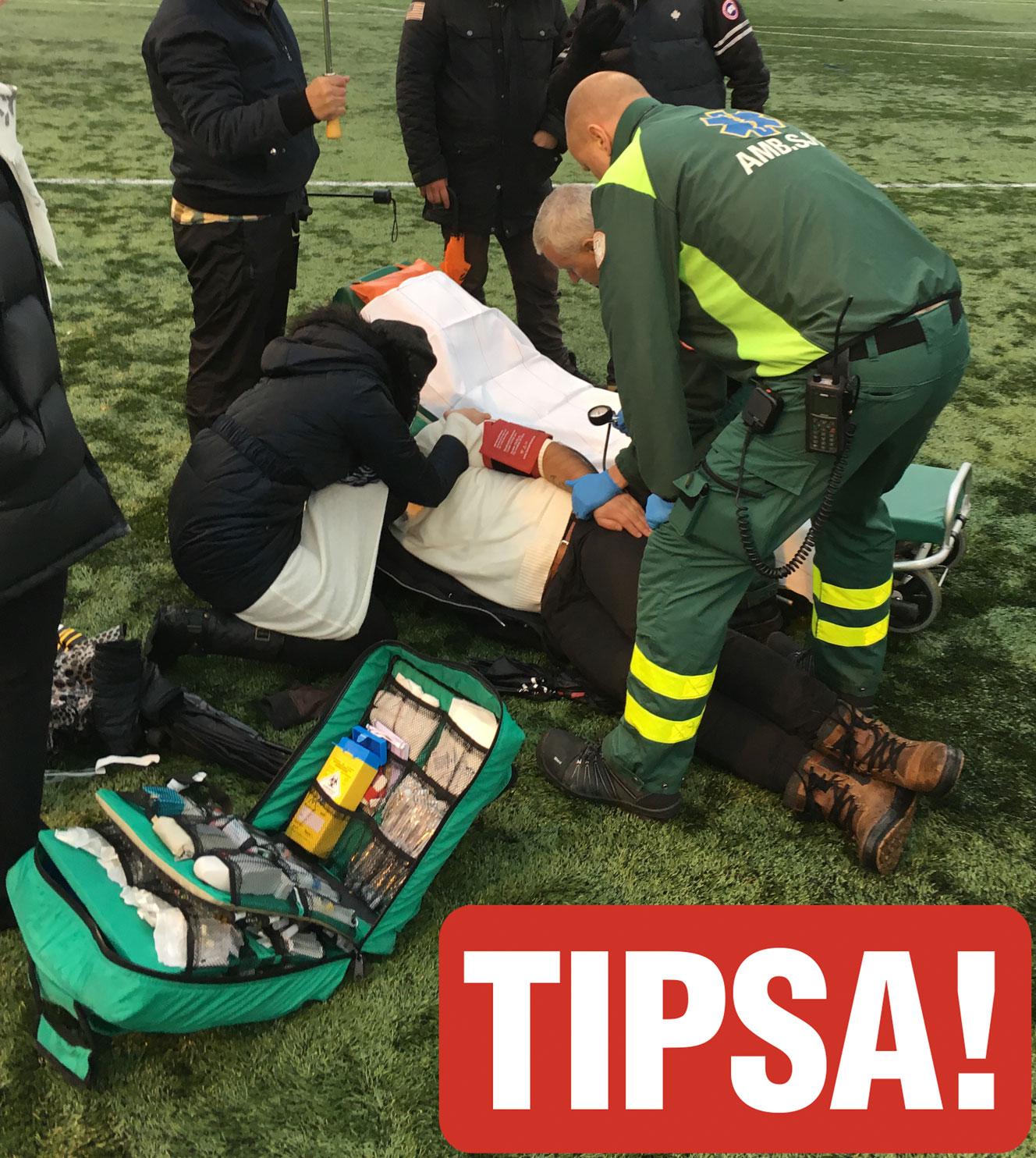 Ambulanssjukvårdare tar om hand om en fotbollsförälder som skadat sig i tumultet.