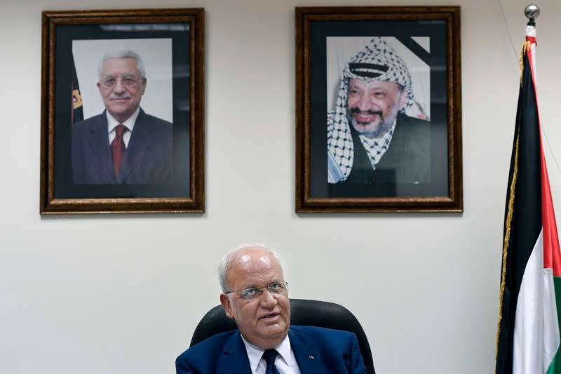 Chefsförhandlare Saeb Erekat på sitt kontor.  Bakom sig har han porträtt av palestiniernas president Mahmoud Abbas och den förre ledaren Yassir Arafat