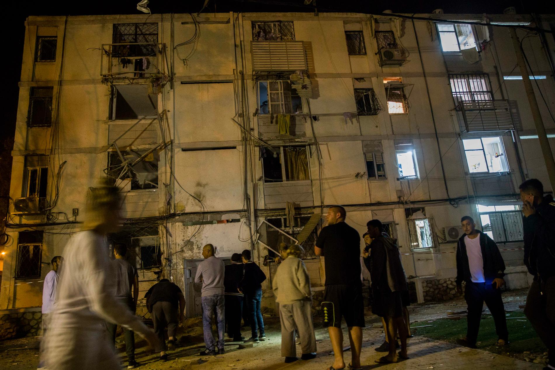 Israeler utanför ett bostadshus i staden Ashkelon som under natten träffats av raketer.