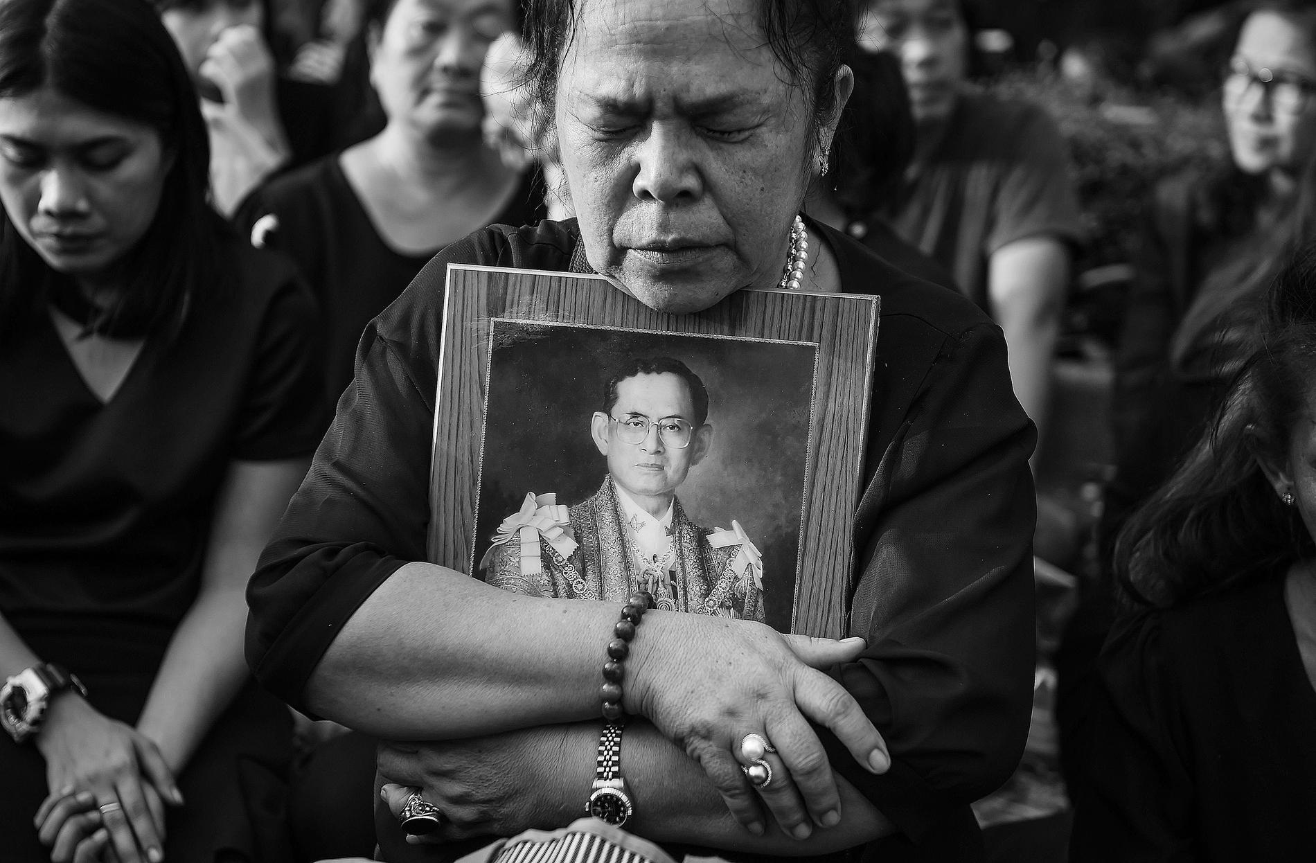 En kvinna kramar om en bild av avlidne kung Bhumibol Adulyadej.