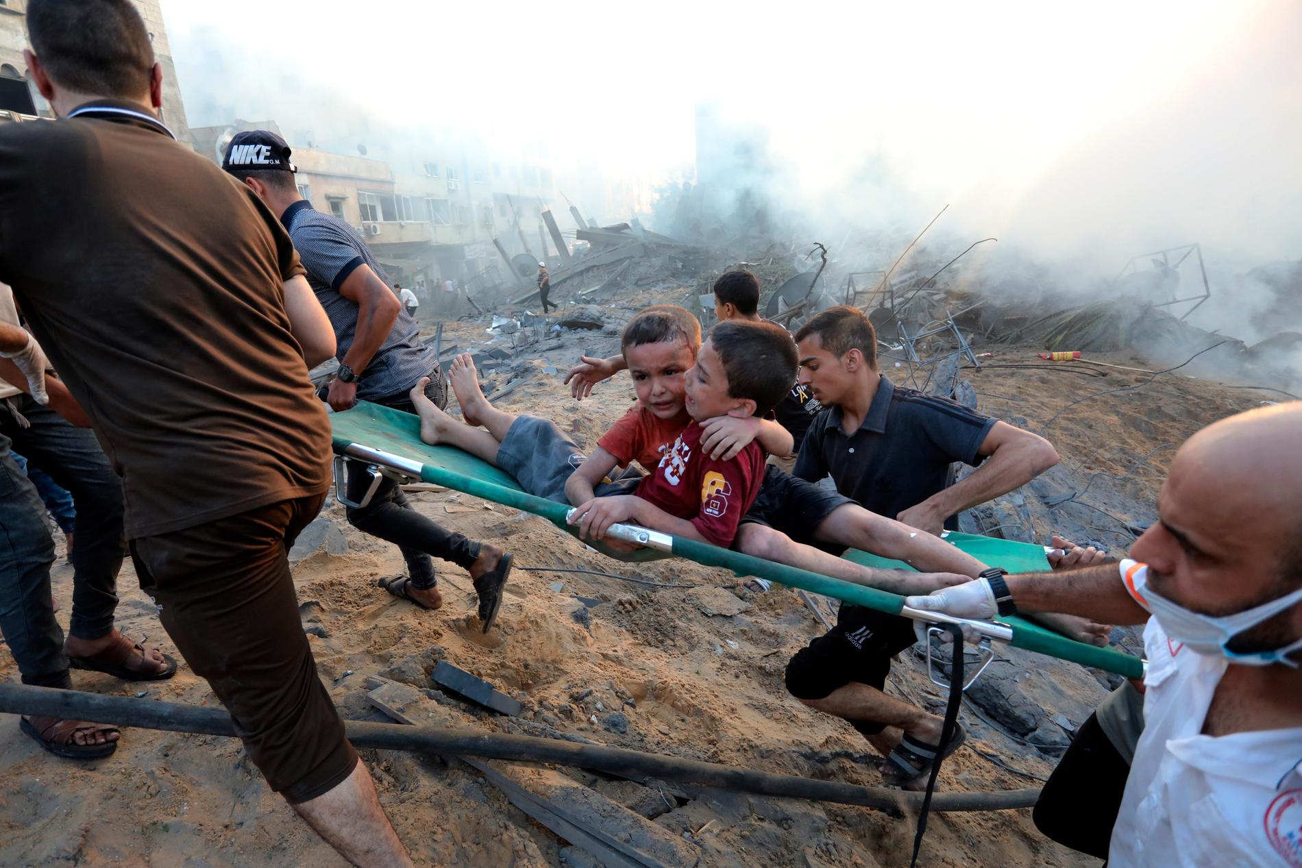 Två skadade pojkar evakueras ur förödelsen efter Israels bomber i Gaza city.