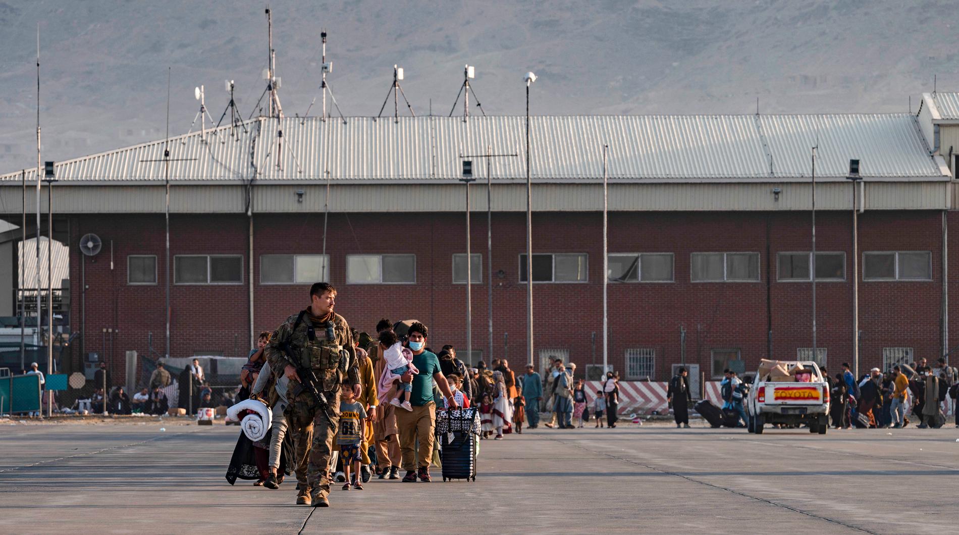 Hamid Karzai internationella flygplats i Kabul i går tisdag. Personal från amerikanska flygvapnet leder människor mot ett evakueringsplan.