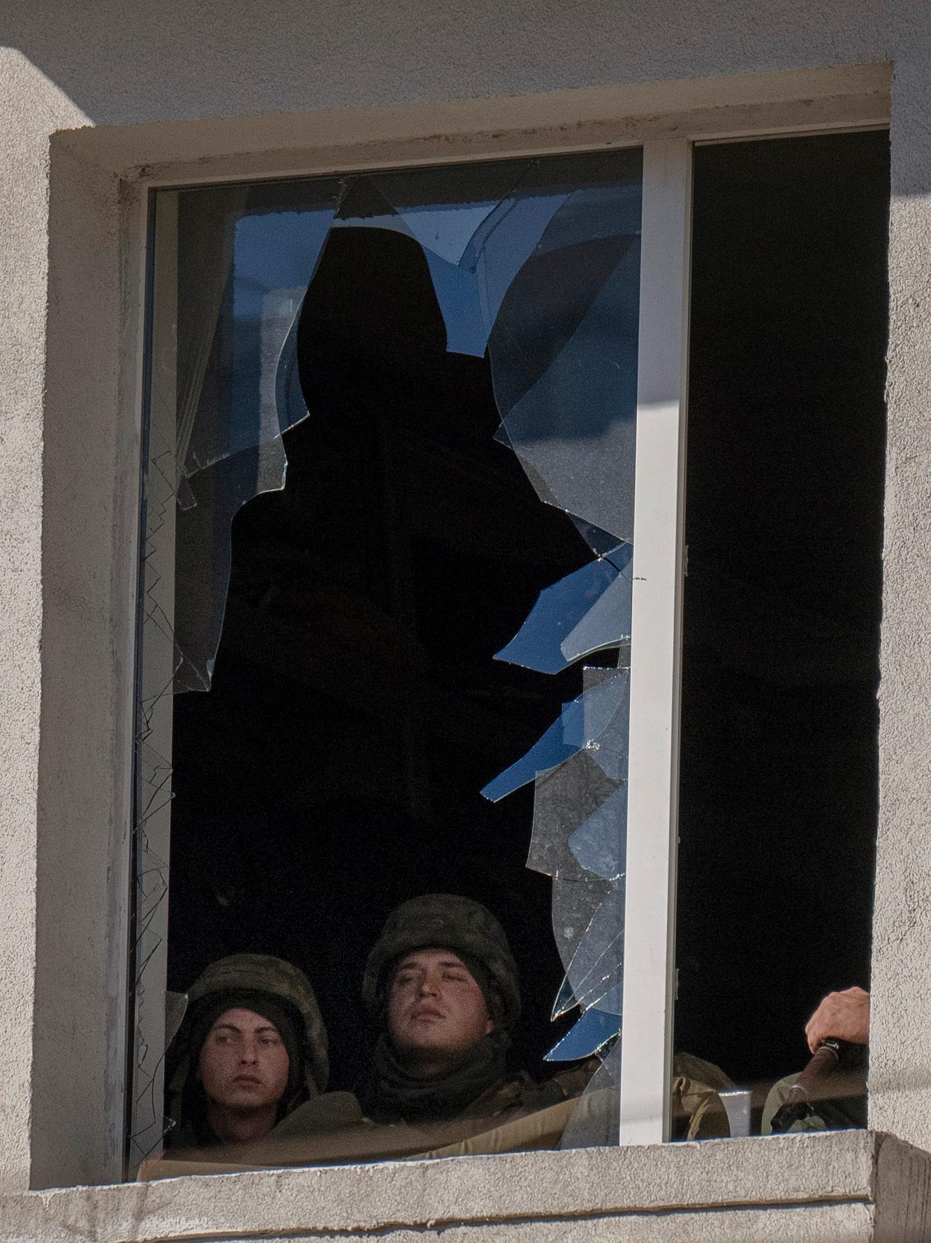 Ukrainska soldater tittar ut från ett trasigt fönster i en militär byggnad i Kiev. 