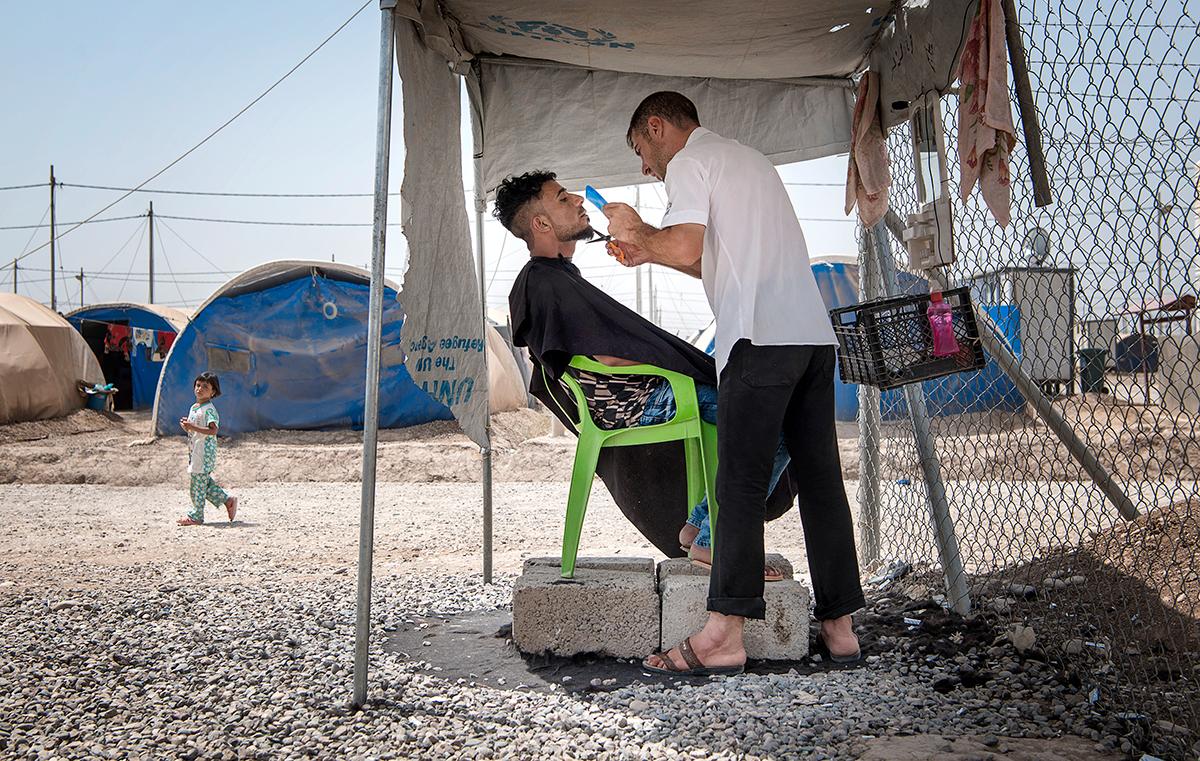 Barberaren Taher Abdelrahim klipper skägget på Haidar Mahmoud i flyktinglägret Khazer under stor koncentration. De båda männen har flytt från Mosul där de tvingades leva under IS våld under flera år.