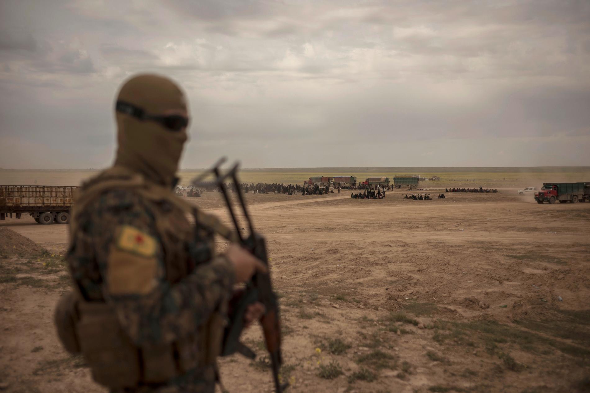 En av SDF:s milismän vaktar ett mottagningsområde för civila som evakuerats från al-Baghuz.