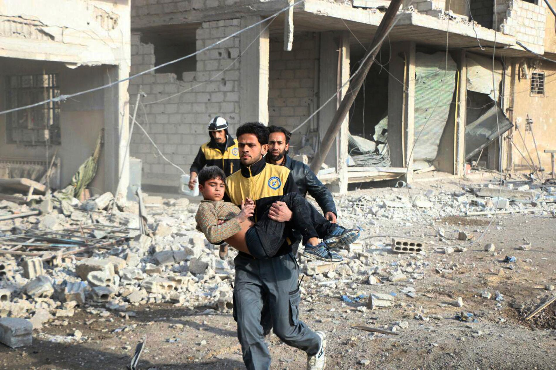 En medlem av den syriska civilförsvarsorganisationen Vita hjälmarna bär en skadad pojke som de räddat under ett flyganfall i östra Ghouta.