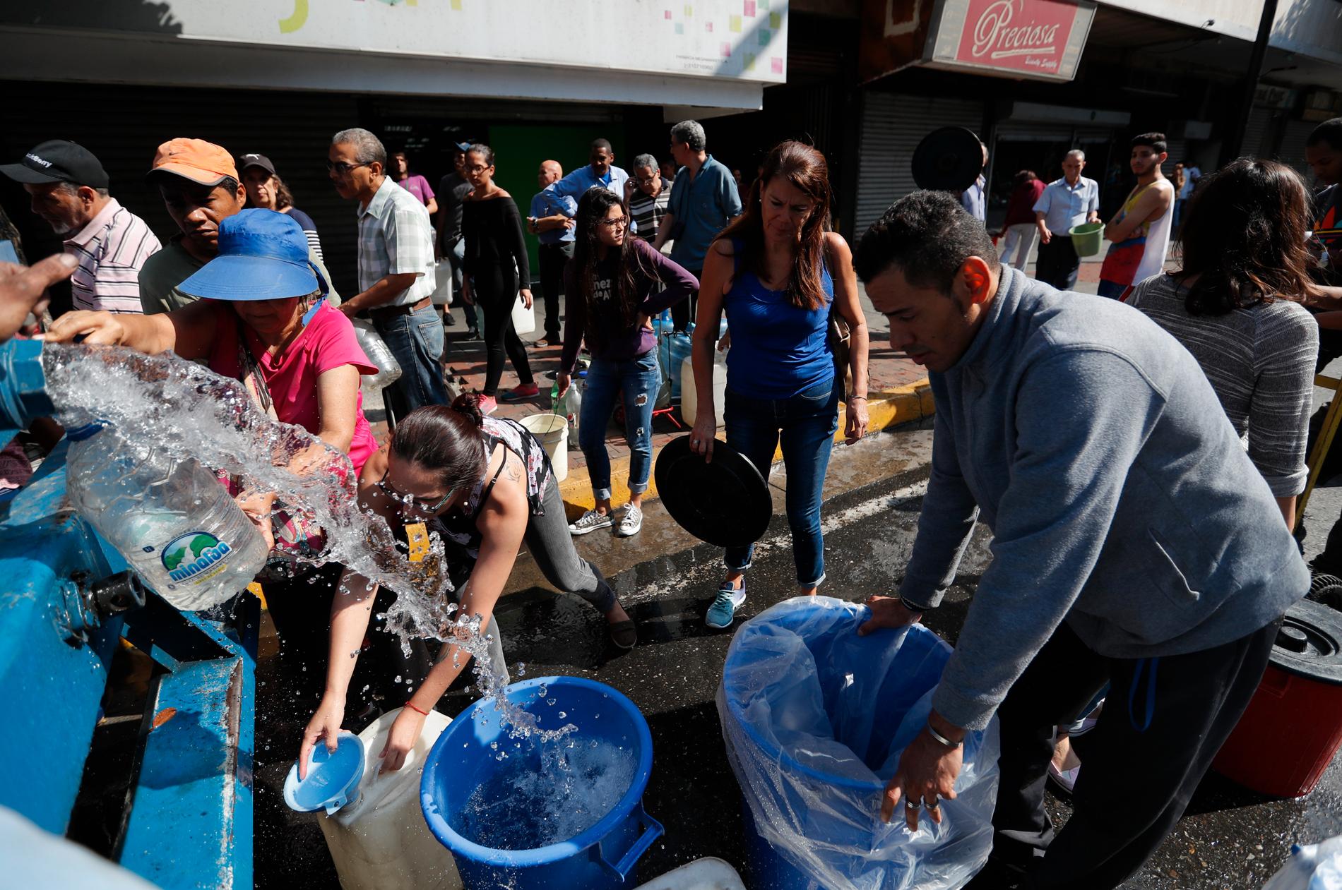 Caracasbor samlar vatten från ett vattentankfordon under det flera dagar långa strömavbrottet i Venezuela nyligen.