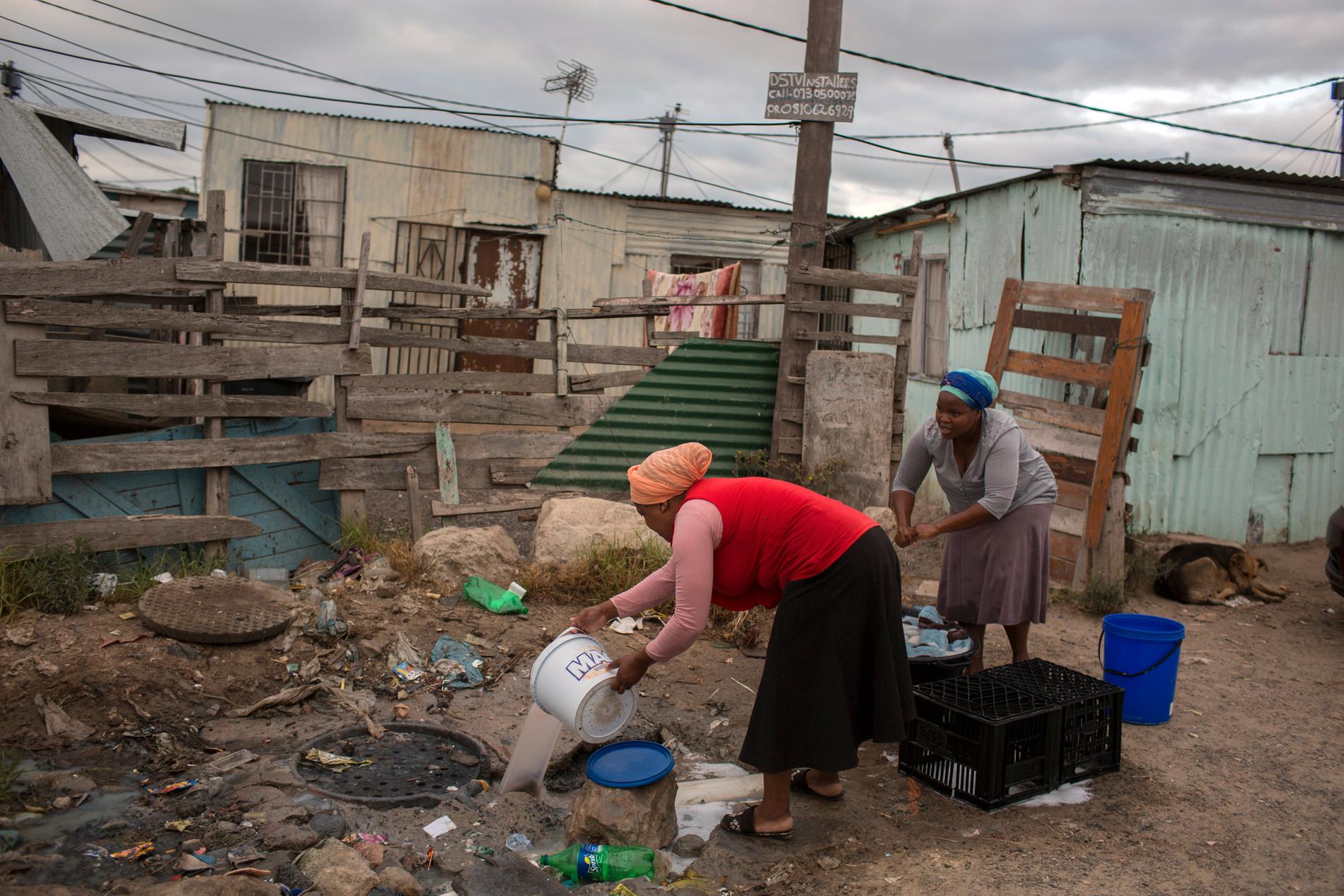 En kvinna häller ut avloppsvatten vid ett bostadsområde utanför Kapstaden, som drabbats hårt av torkan.