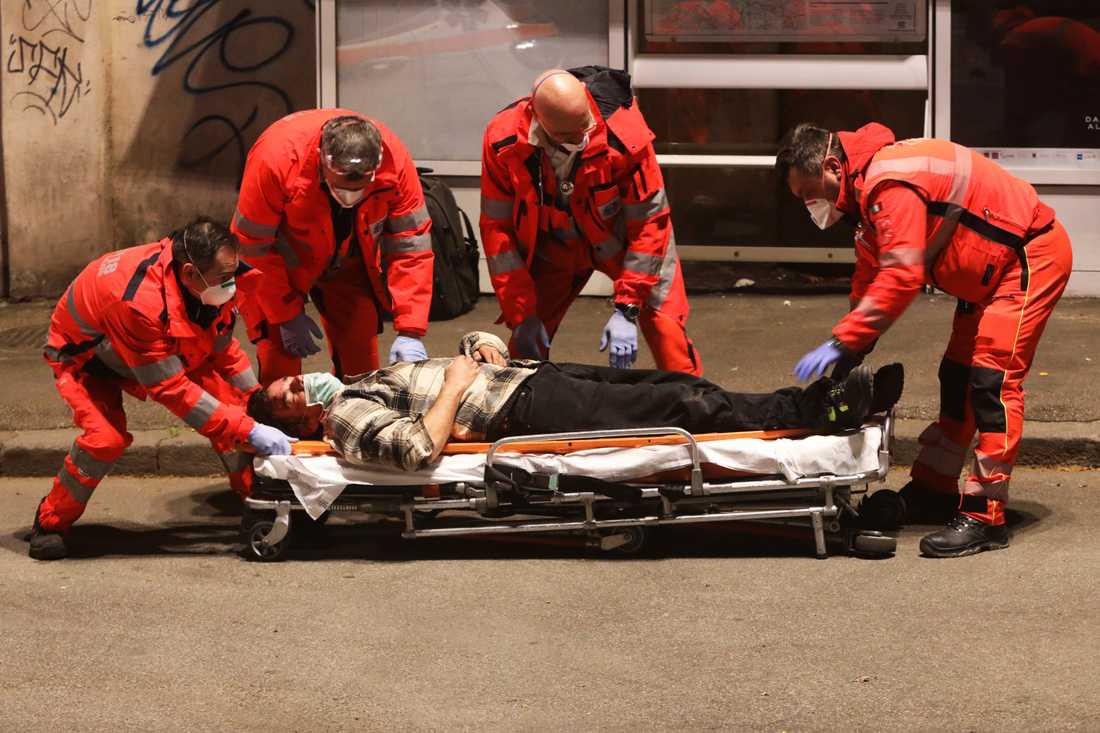 En medvetslös man som kollapsat på gatan, tas om hand av ambulanspersonal i Rom.