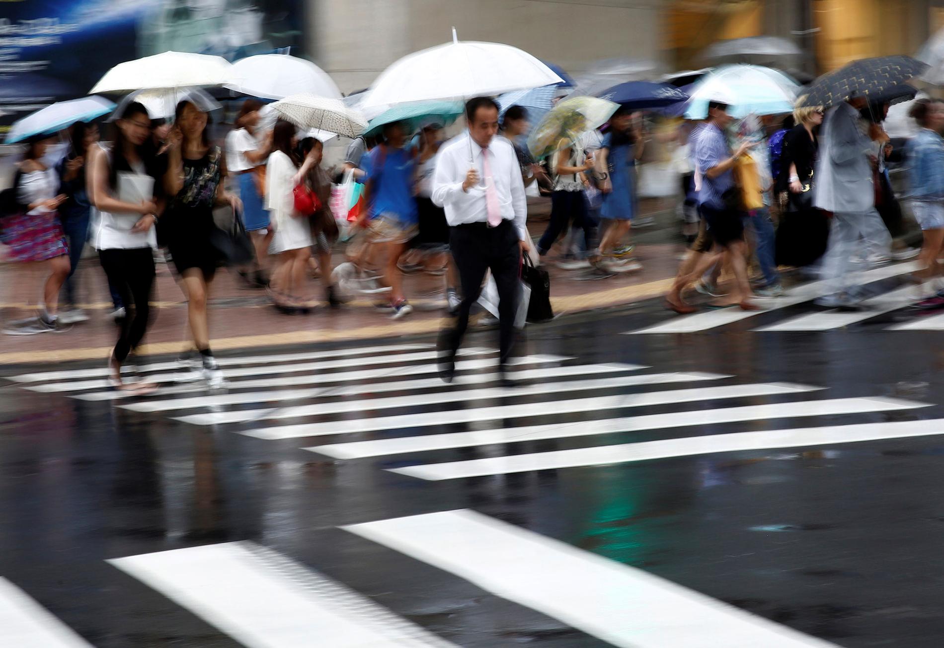 En man skyndar över gatan i regnet i finansdistriktet i Tokyo, Japan.
