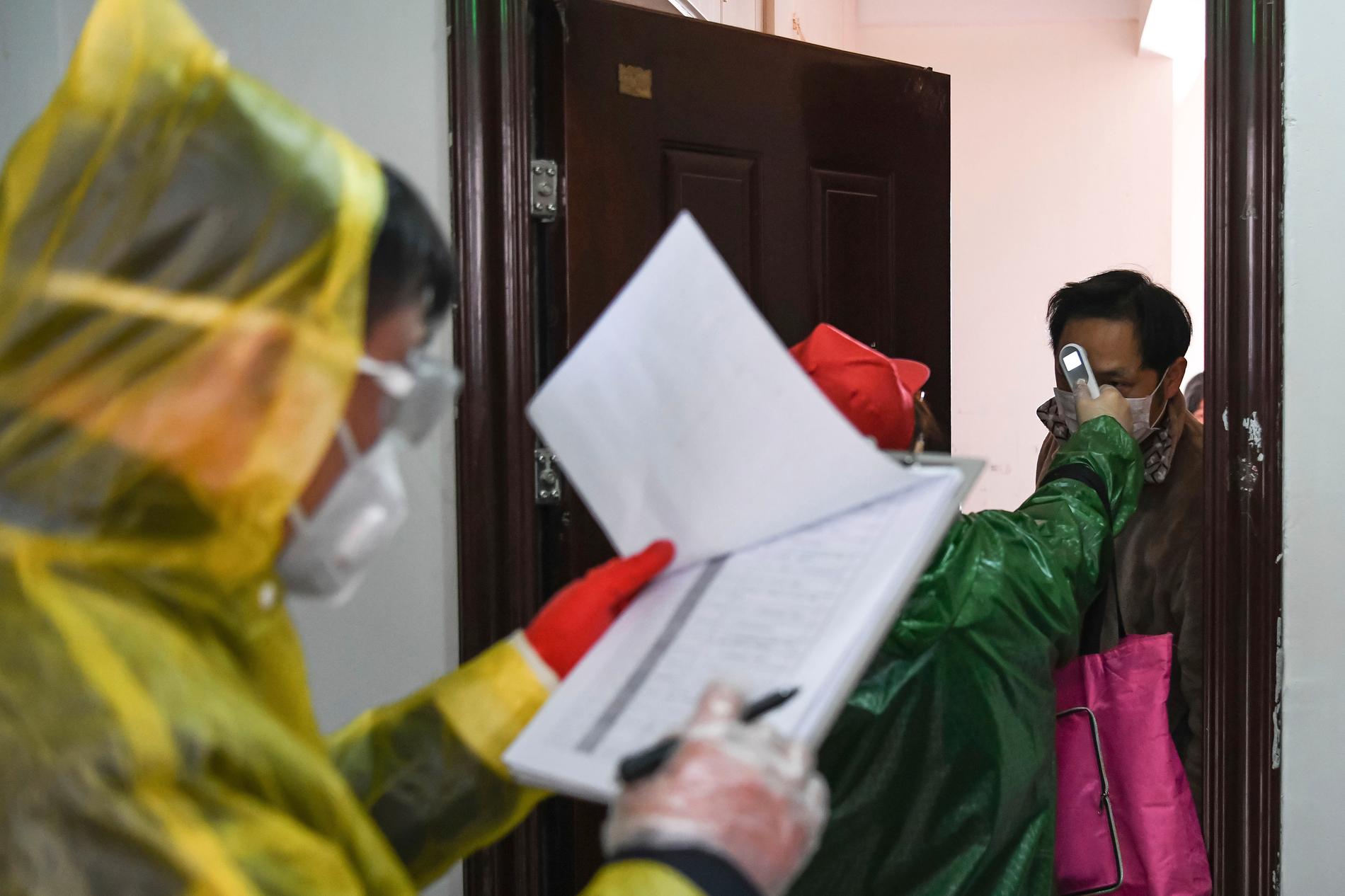 Invånare i Wuhan kontrolleras för feber i en dörrknackningskampanj. Bild från tidigare i veckan.