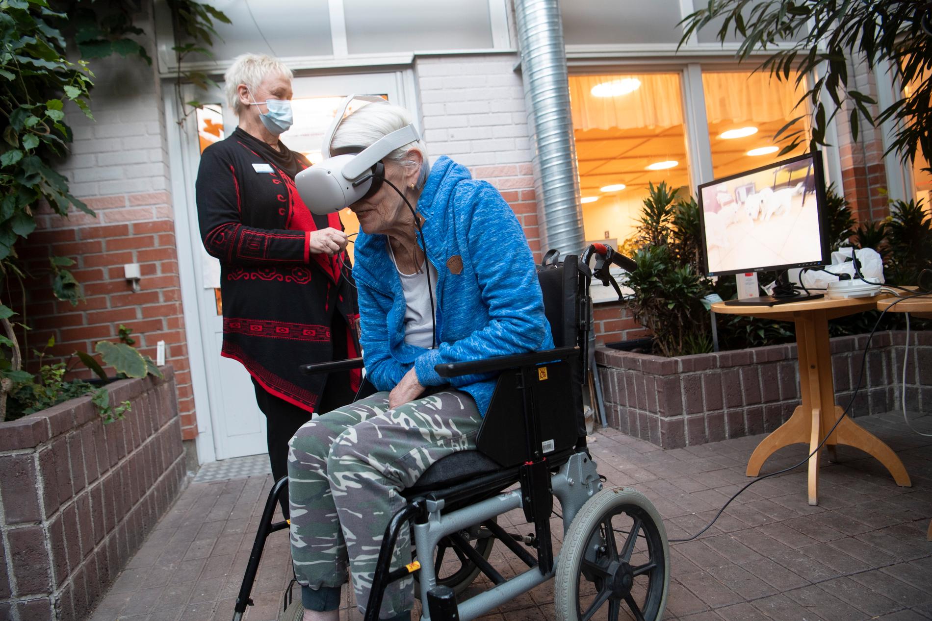 Undersköterska Lotta Andréasson hjälper boende Maud Sjölander, boende på äldreboendet Vallongården, att möta hundvalpar med hjälp av VR-glasögon.
