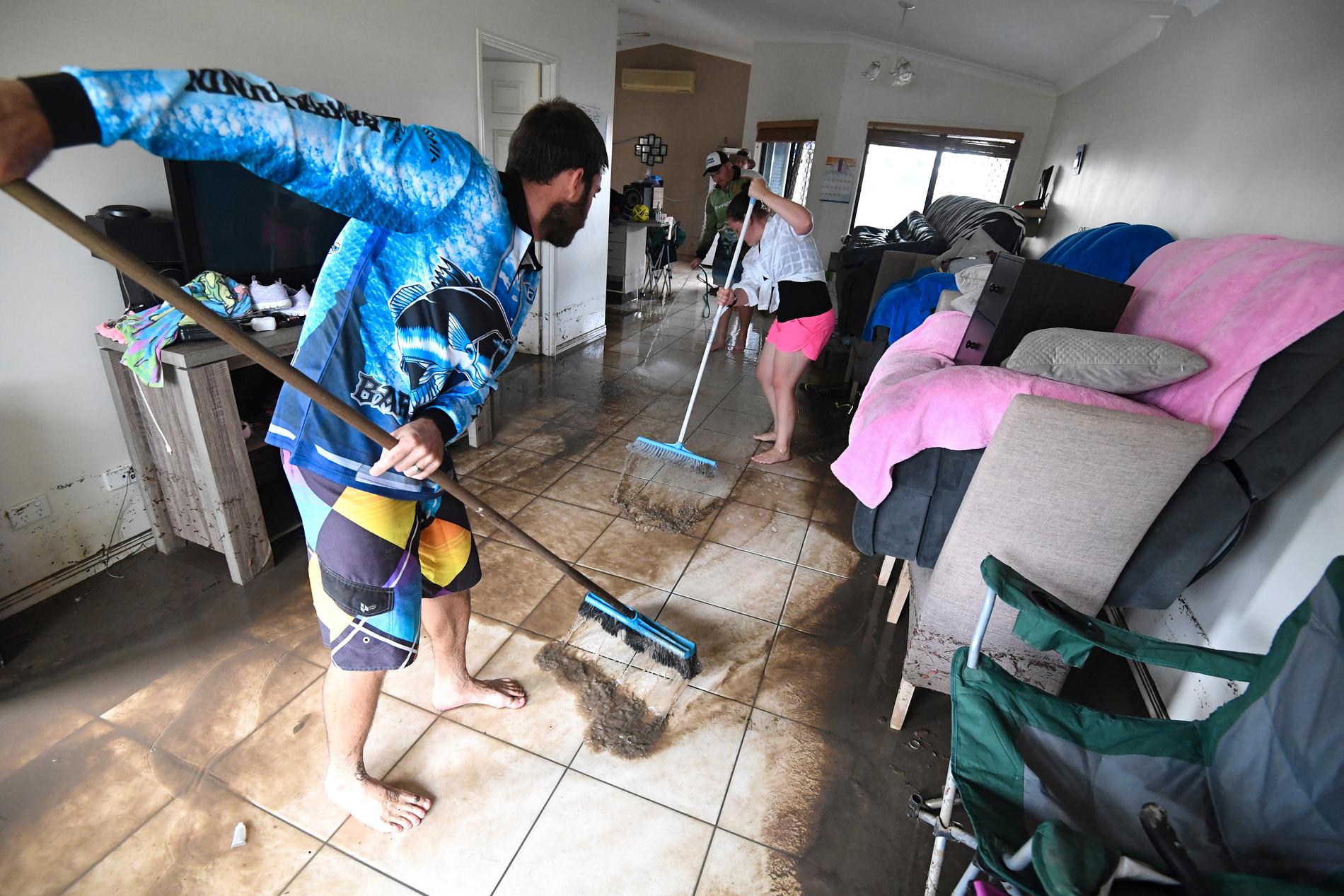 Townsvillebor städar bort lera efter översvämningarna i Australien.
