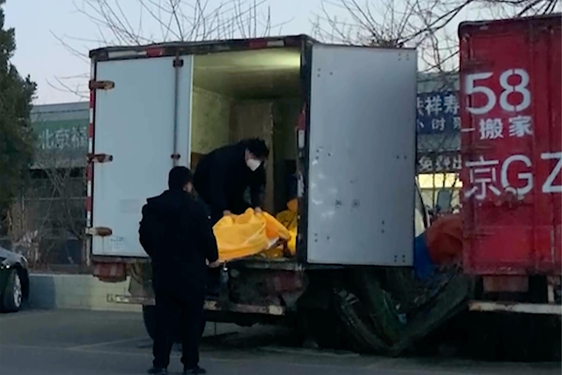Döda i liksäckar lastas i ett fordon vid en begravningsbyrå i Peking. Arkivbild.