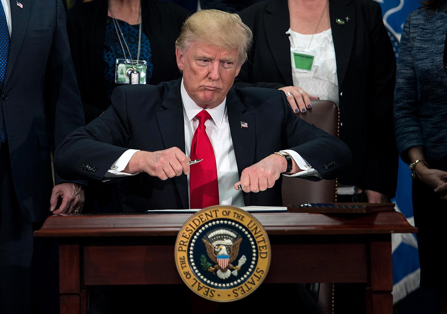 Trump tar av locket på pennan för att signera den exekutiva ordern om att bygga muren mot Mexiko.