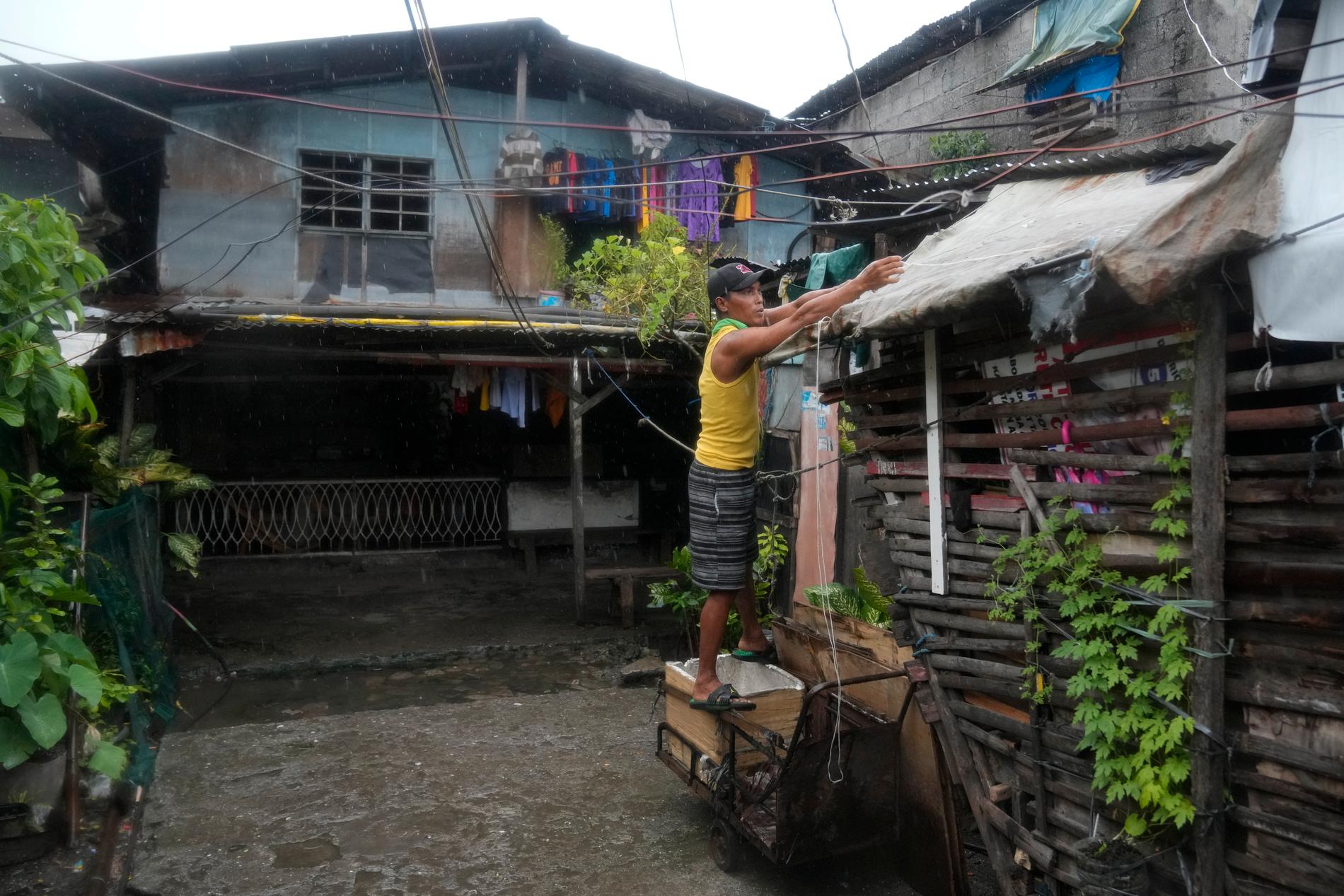 En boende i det fattiga distriktet Tondo i Manila förstärker sitt tak för att skydda sig mot tyfonen Noru.
