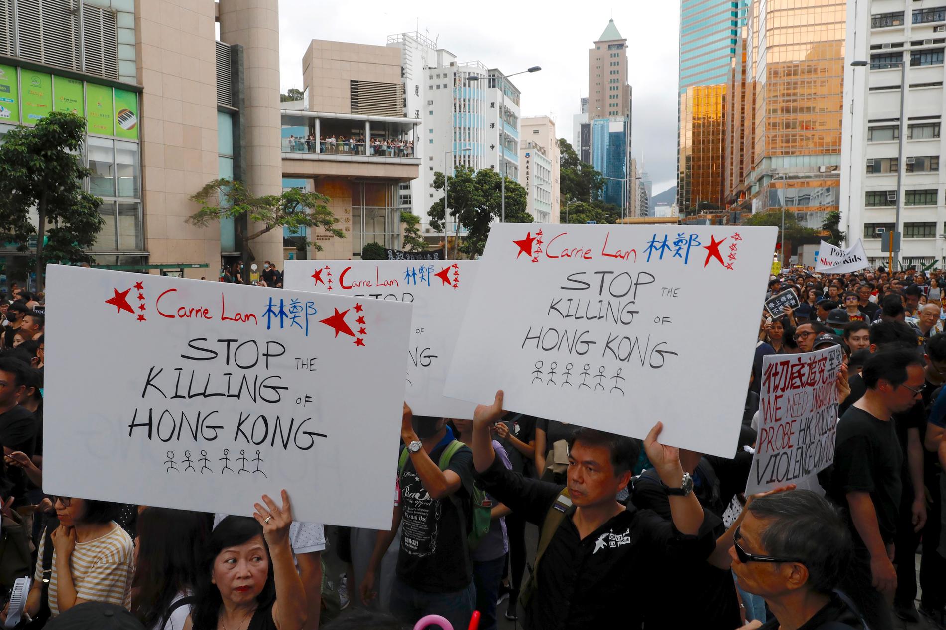 Demonstranter håller upp sina budskap under söndagens protestmarsch i Hongkong.
