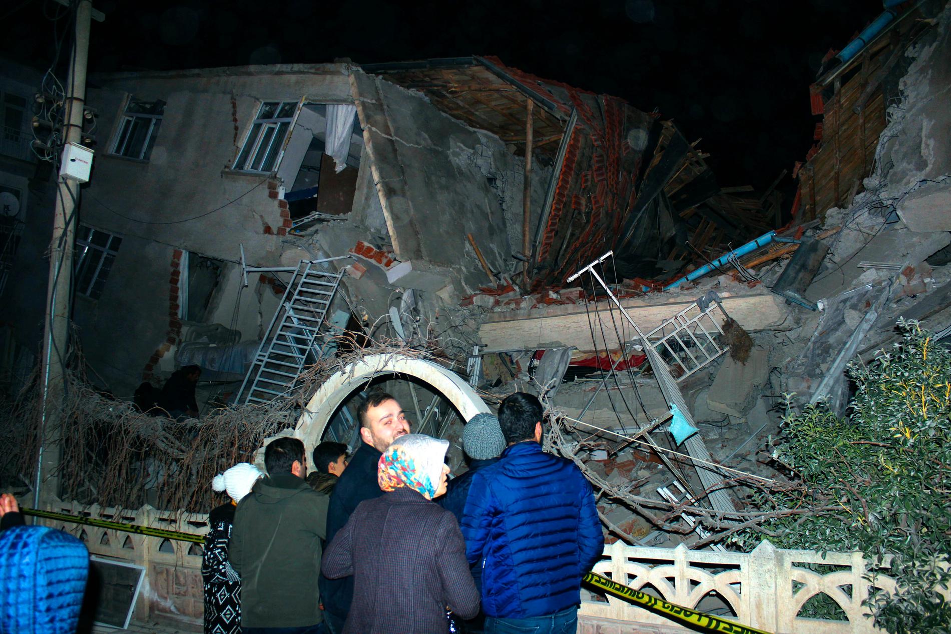 Människor framför en byggnad som rasat samman i staden Elazig i östra Turkiet. Minst fyra människor dog i en kraftig jordbävning.