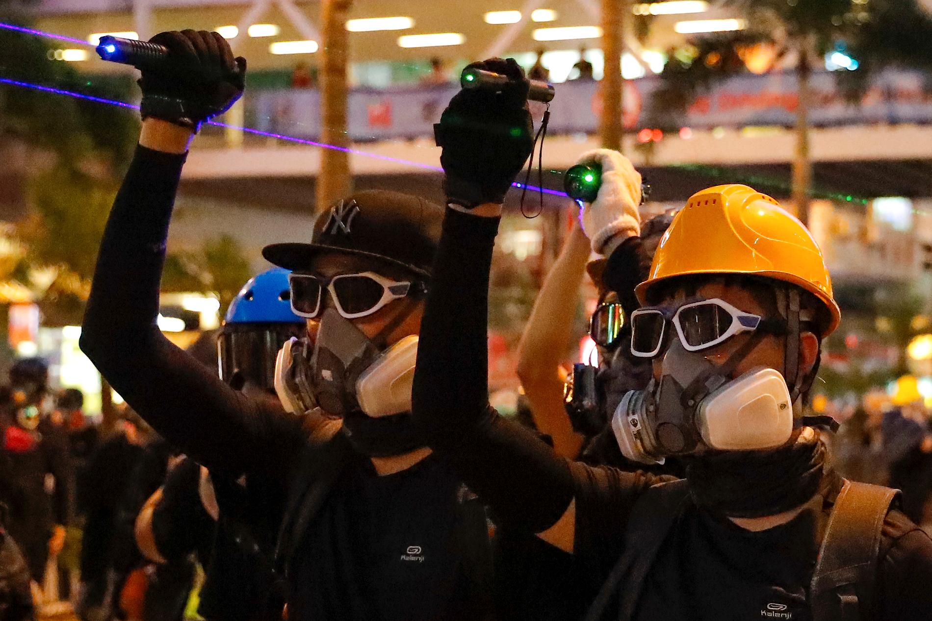 Demonstranter med andningsskydd mot tårgasen använder laserpekare mot kravallpoliser under söndagens protester i Hongkong.