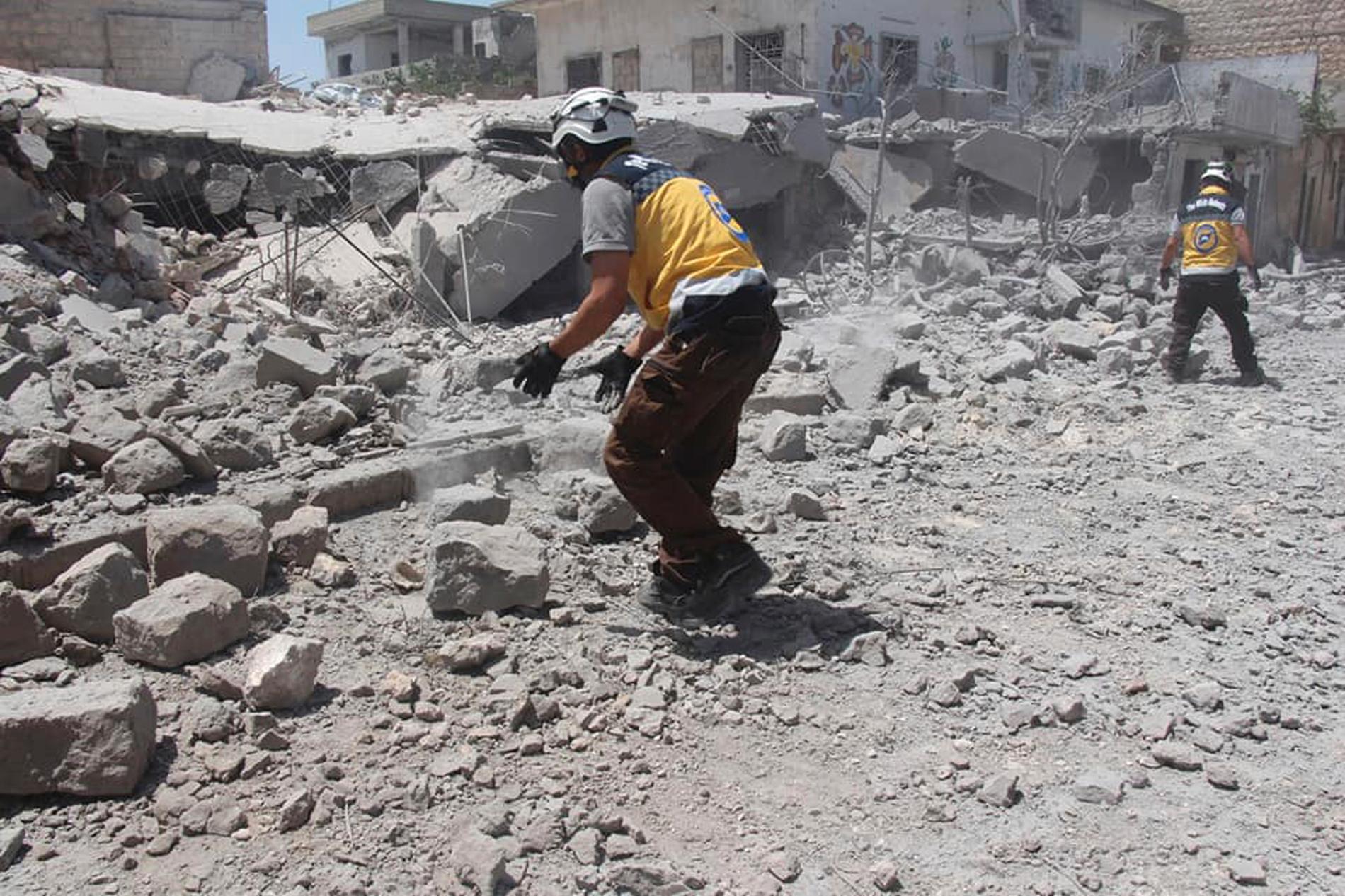 En bild tagen av civilförsvaret Vita hjälmarna, och vars äkthet har verifierats av nyhetsbyrån AP, visar räddningsarbetare i rasmassor efter ett flyganfall i södra Idlibprovinsen den 1 juni.