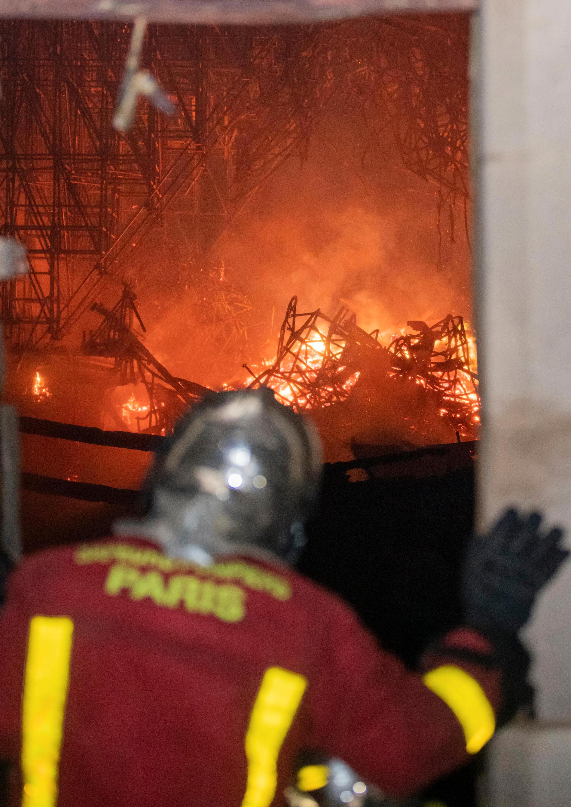 Person ur brandkåren tittar på branden i Notre-Dame. 