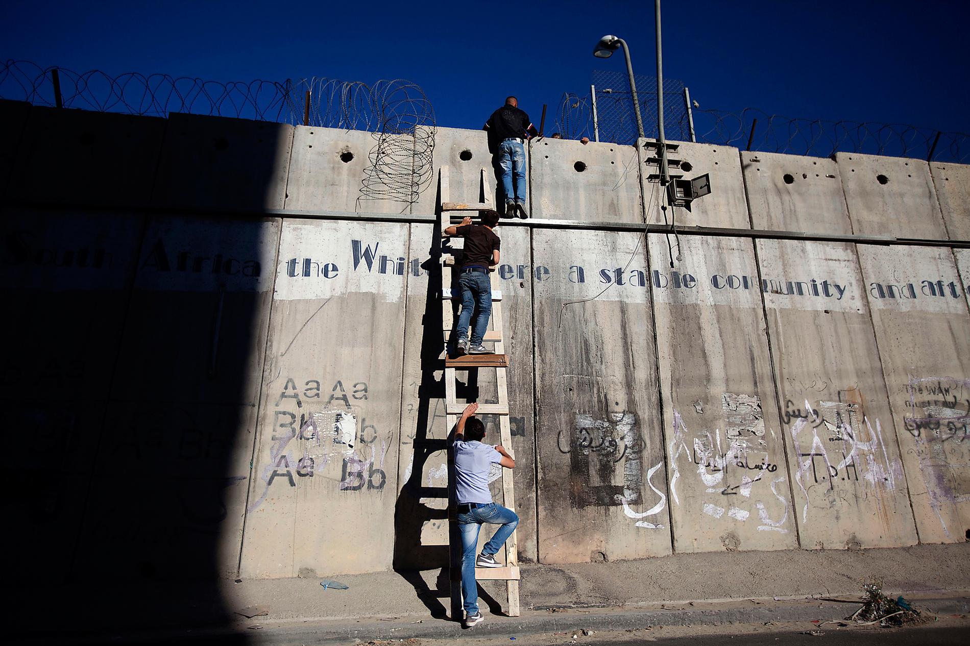 Murar är till för att rivas Idag skär den israeliska muren sönder landet. Palestinierna stängs ute eller tvingas, som här, att klättra för att ta sig till moskén. Men en dag kommer den, som alla murar, att rivas. Foto: Majdi Mohammed/AP.