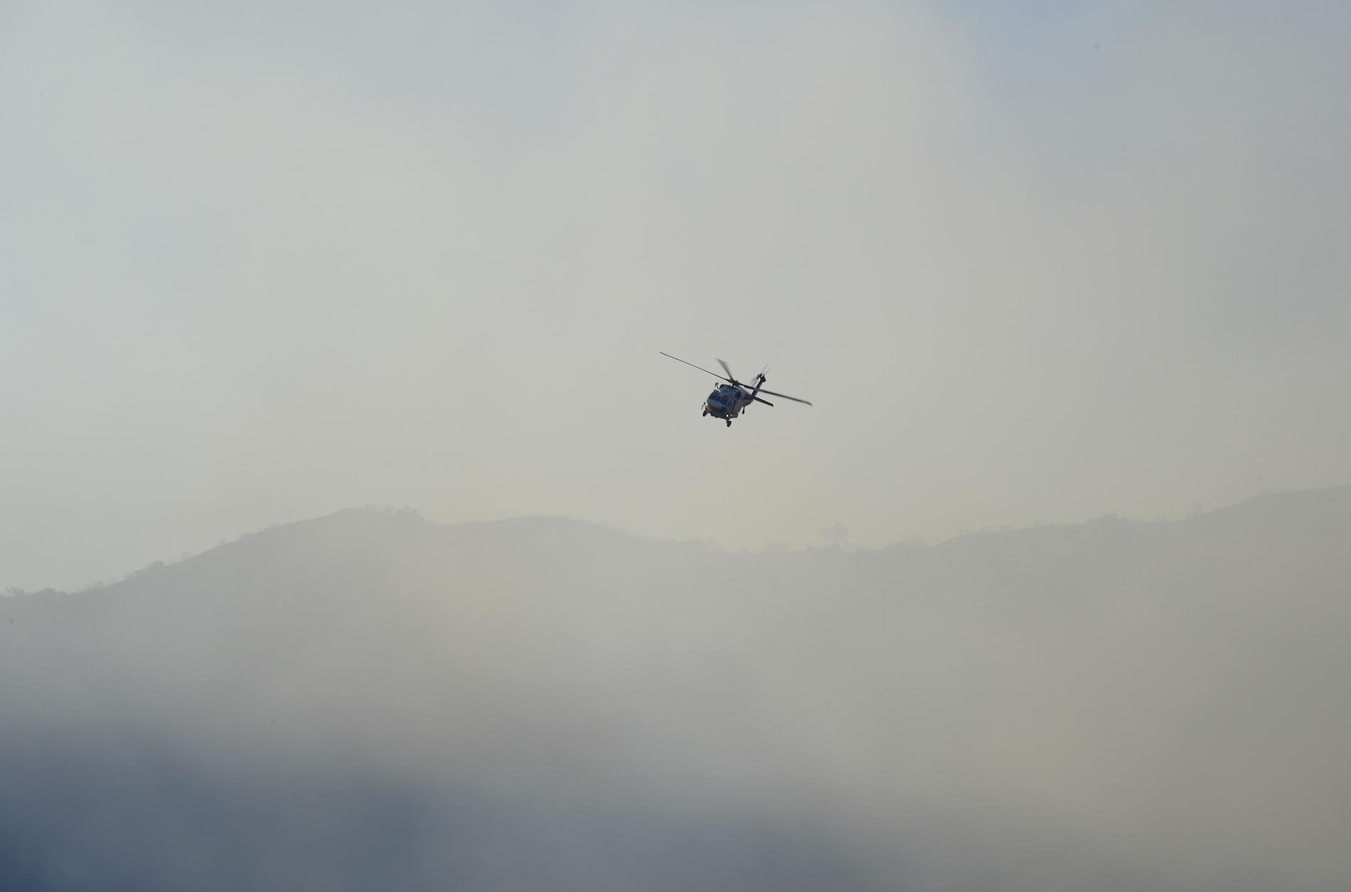 En räddningshelikopter flyger över bränderna. 