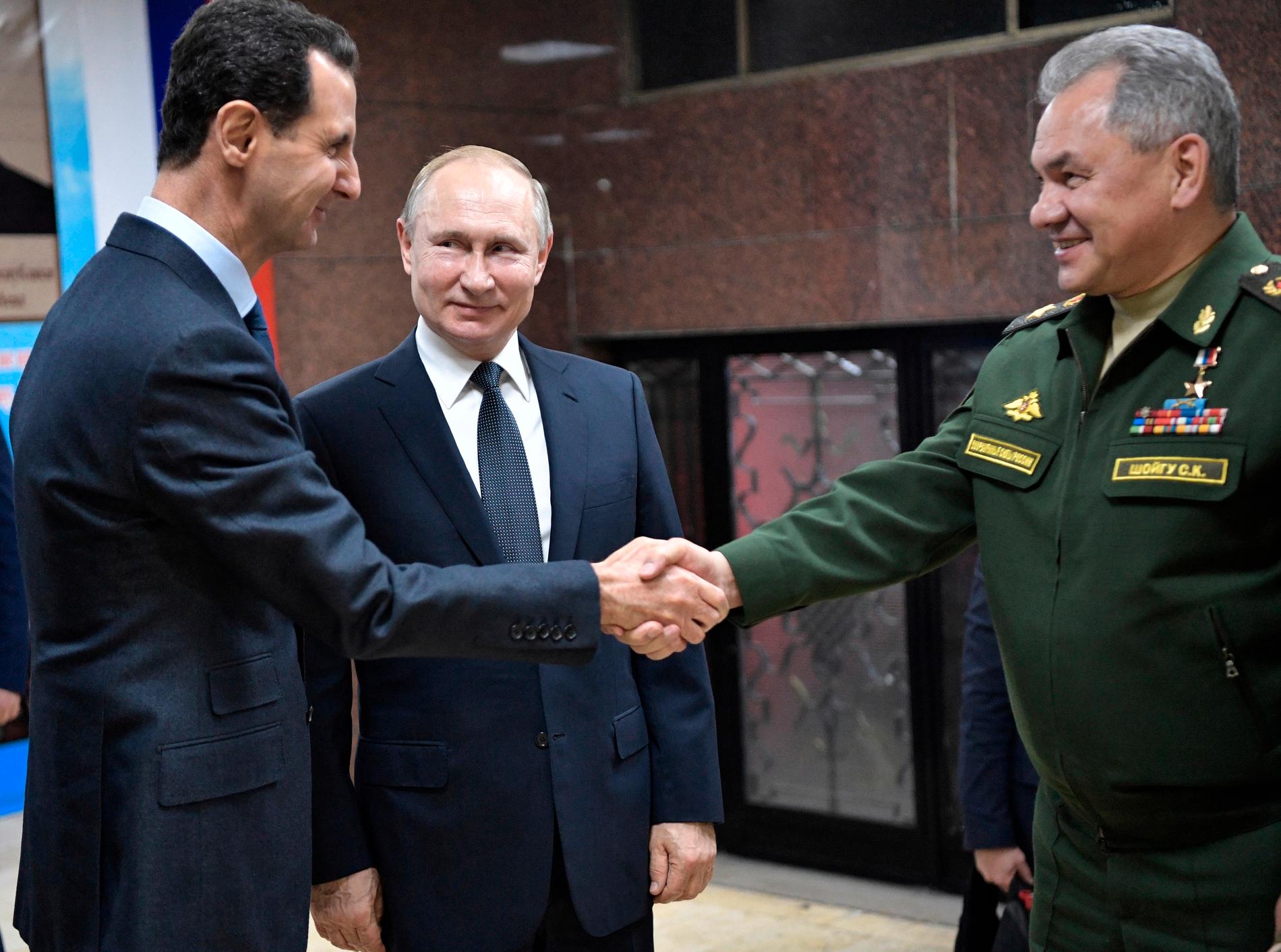 Syriens president Assad hälsar på ryske försvarsministern Sergei Shoigu. I mitten rysslands president Putin. Arkivbild.