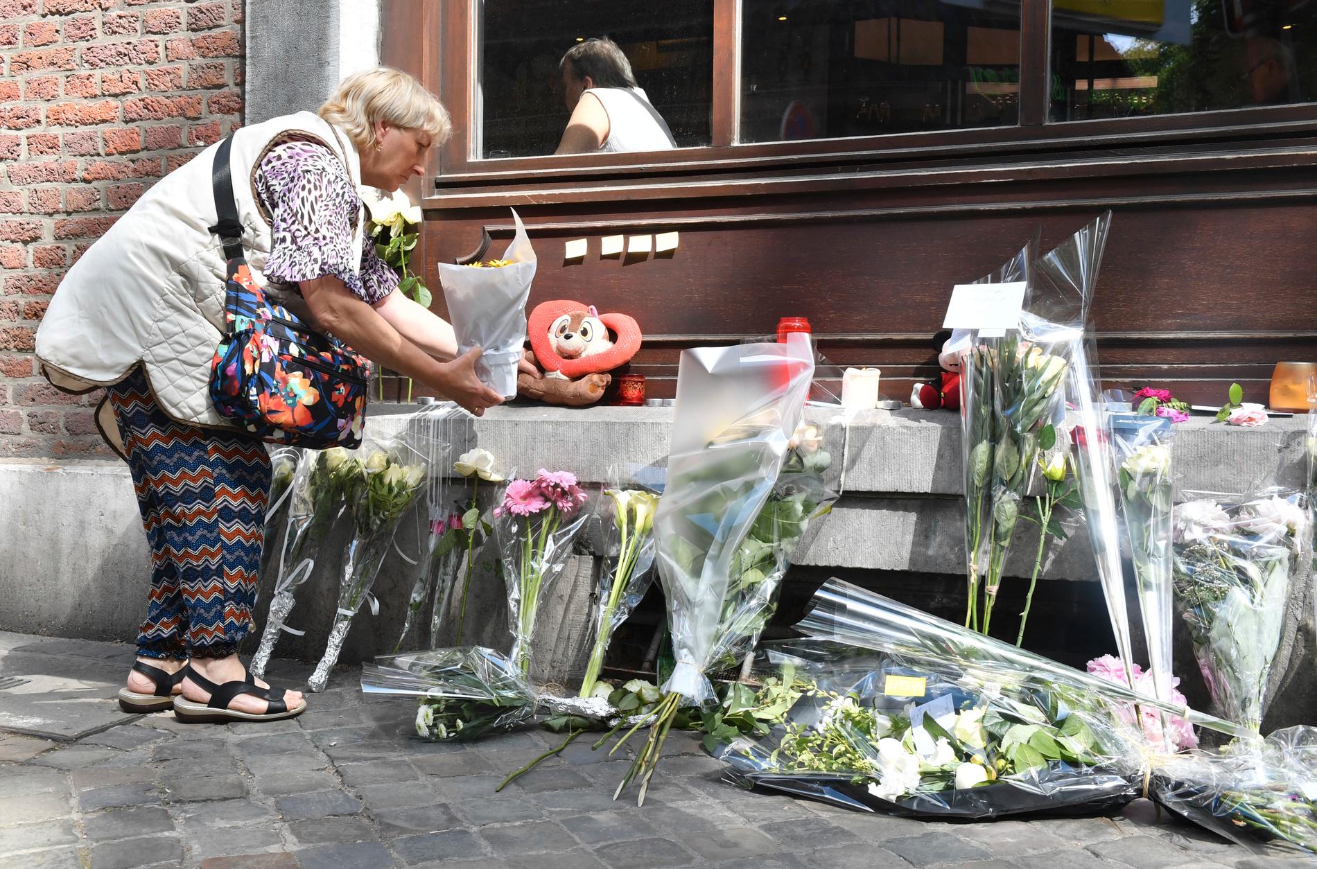 En kvinna lägger blommor vid minnesplatsen i Liège där tre personer sköts ihjäl i tisdags.