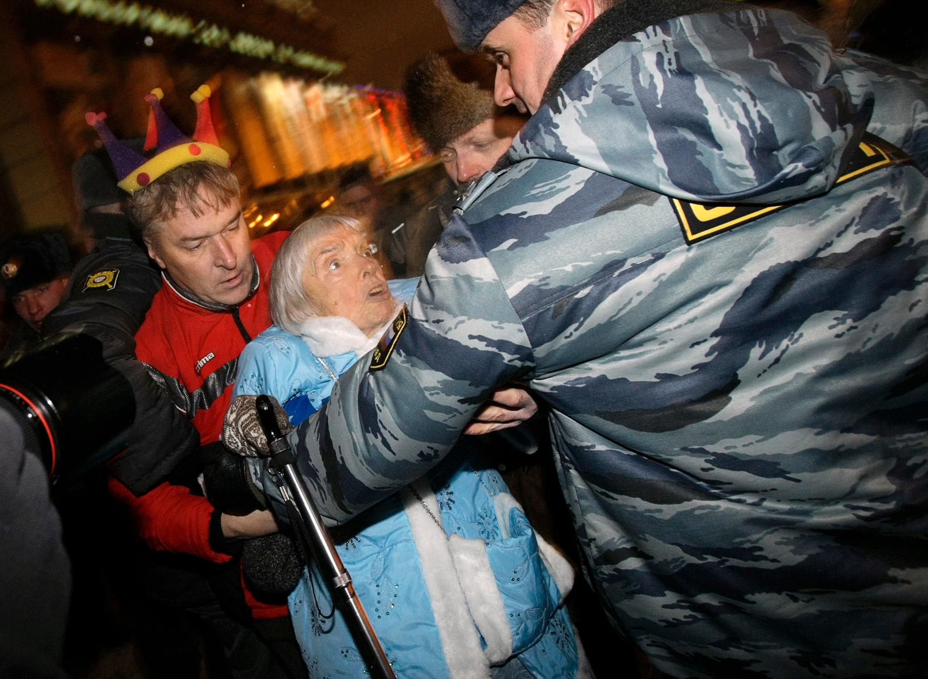 Polis griper Ljudmila Aleksejeva i samband med regeringskritiska protester i Moskva på nyårsafton 2009. Aleksejeva var då 82 år gammal.