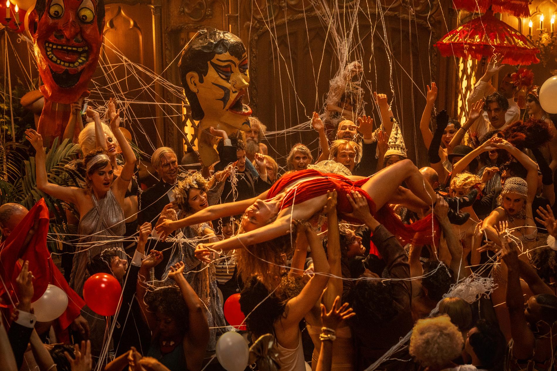 Margot Robbie bärs runt under en av de storslagna festscenerna i "Babylon". Pressbild.