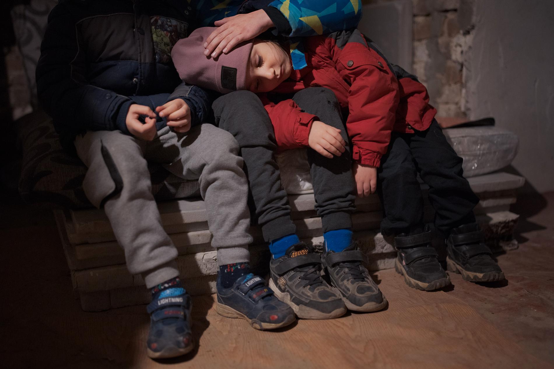 Fyraåriga Kateryna lutar sitt huvud mot storebröderna Taras och Oleksis knän.