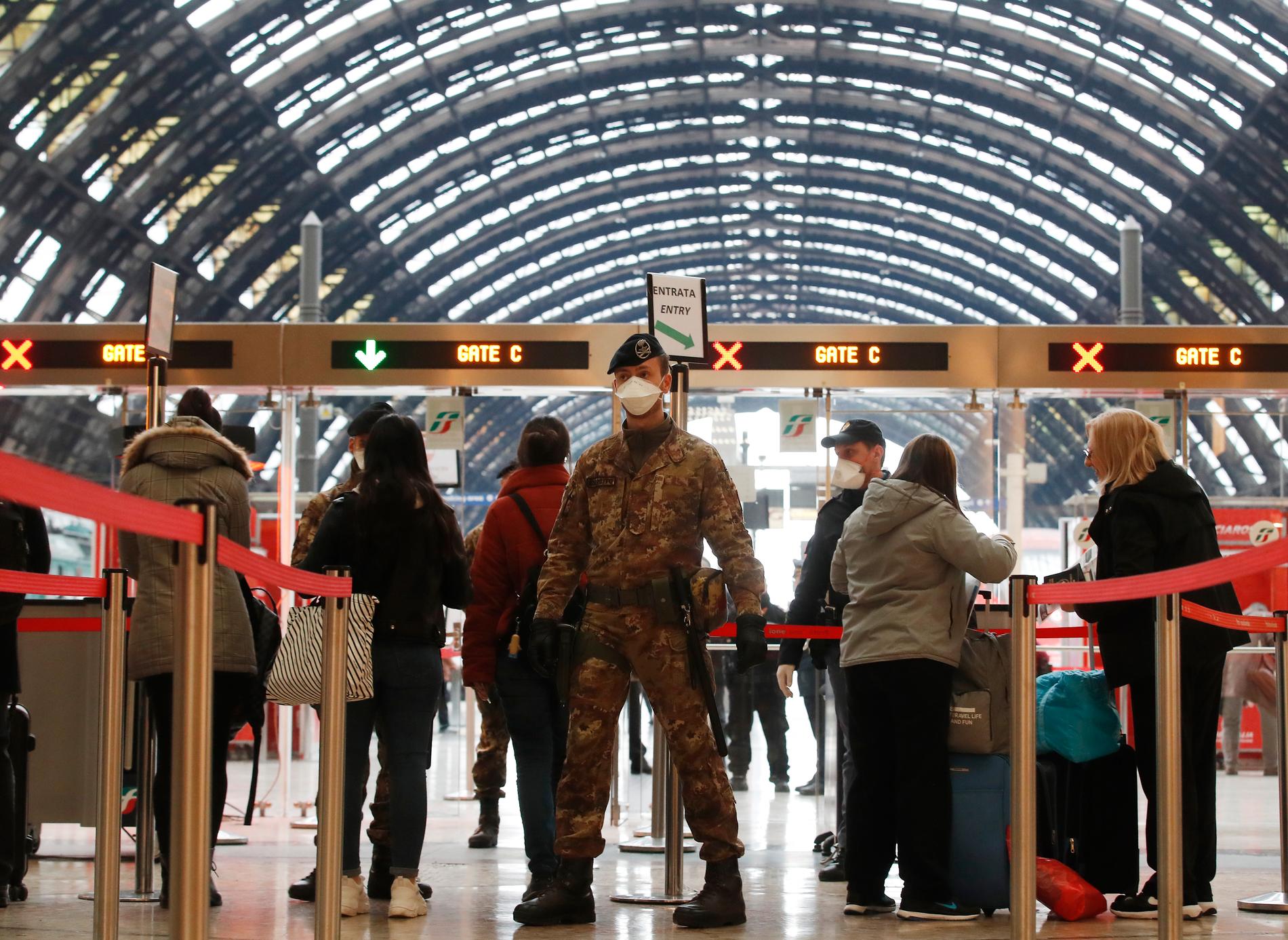 Poliser och soldater kontrollerar passagerare vid tågstationen i Milano.