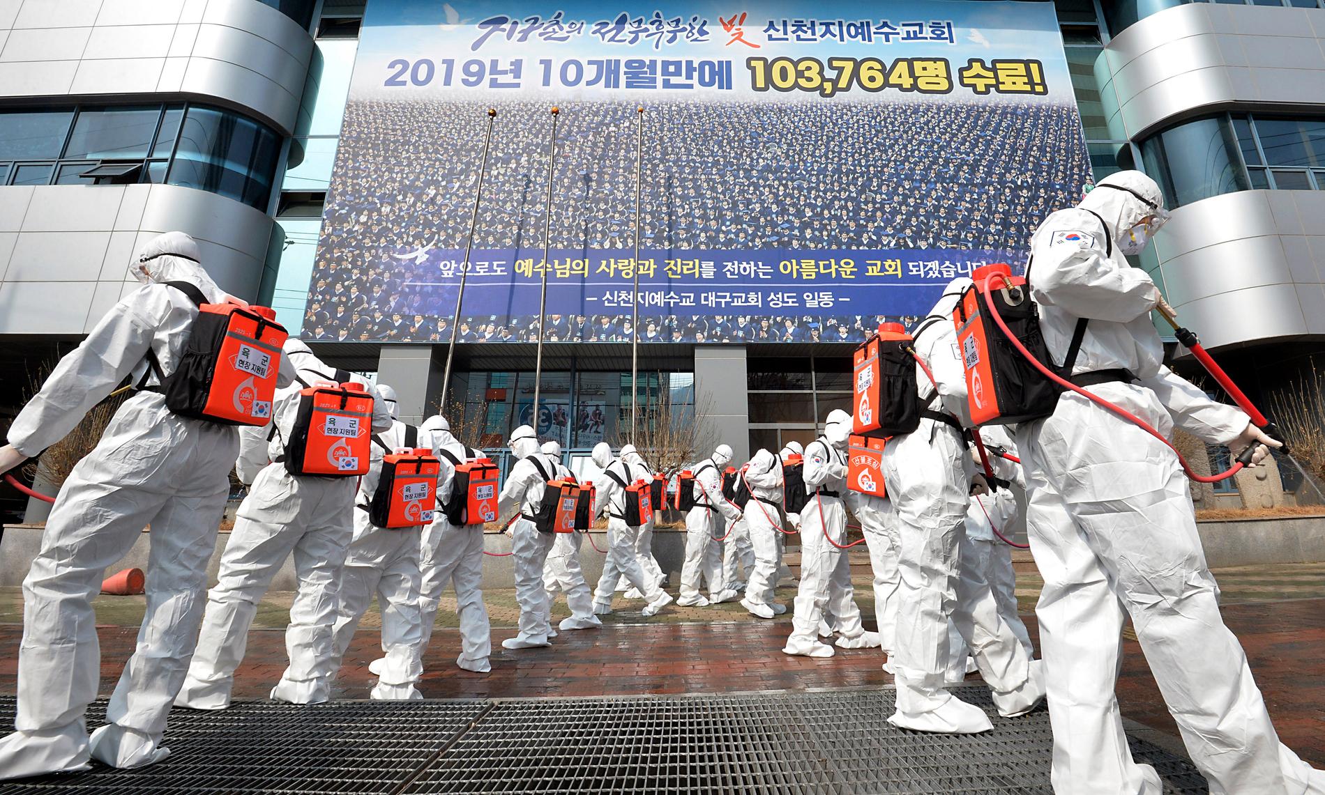 Soldater klädda i skyddsutrustning sprejar disinfektionsmedel för att förhindra smittspridning utanför Shincheonjikyrkan i Daegu. Arkivbild.