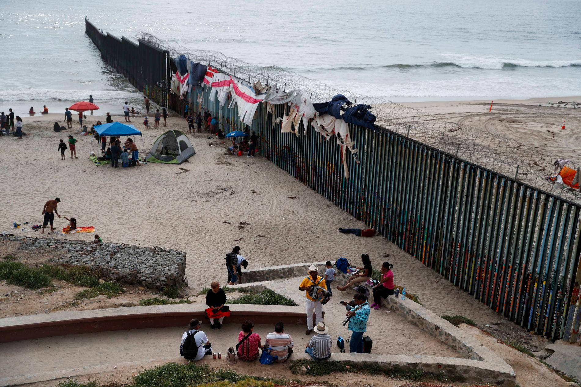 Musiker spelar på stranden intill den taggtrådsförsedda gränsmuren i Tijuana, Mexiko. Arkivbild.