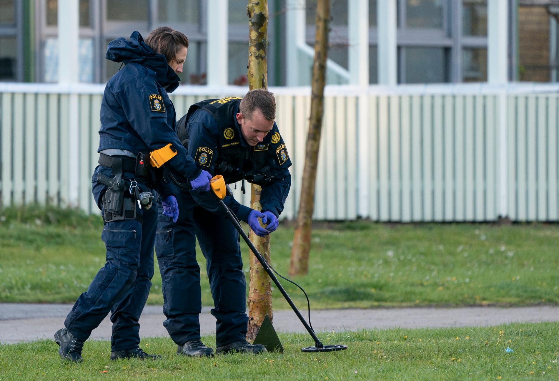 Polisens kriminaltekniker söker med metalldetektor innanför avspärrningen vid en cykelbana vid Almgården/Höja i Malmö på fredagskvällen.