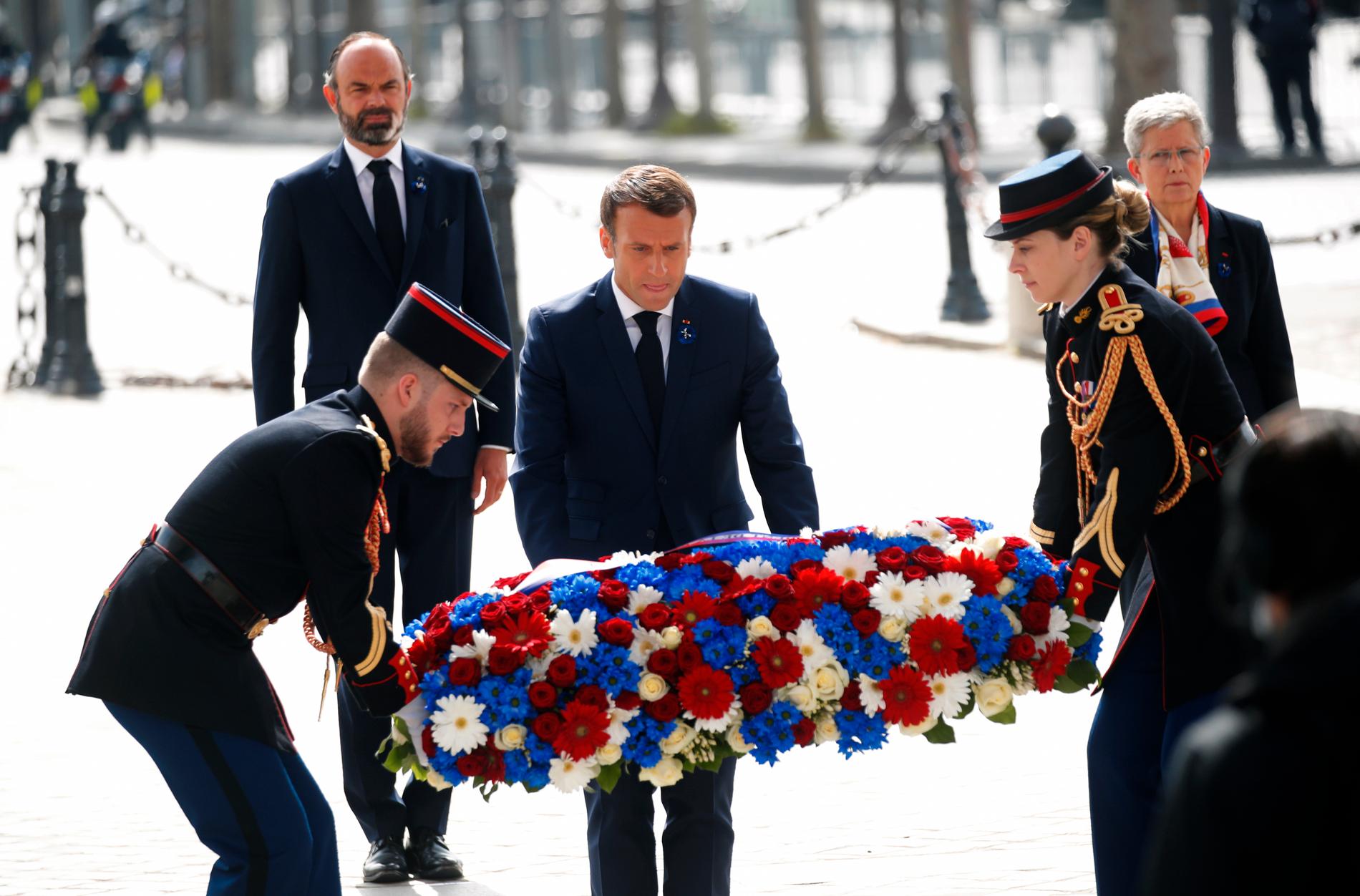 Emmanuel Macron hjälper till med kransen vid Triumfbågen i Paris.