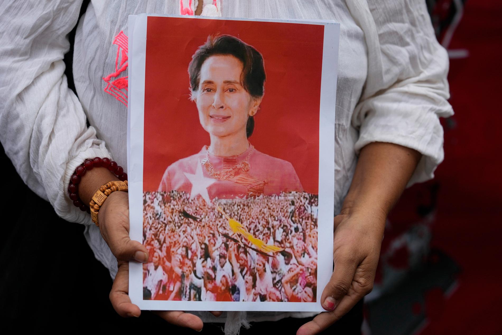 En anhängare håller upp ett porträtt av Aung San Suu Kyi.