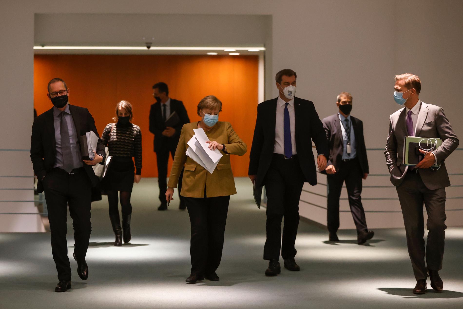 Angela Merkel (i mitten) på väg till presskonferensen där de nya coronaåtgärderna presenterades.