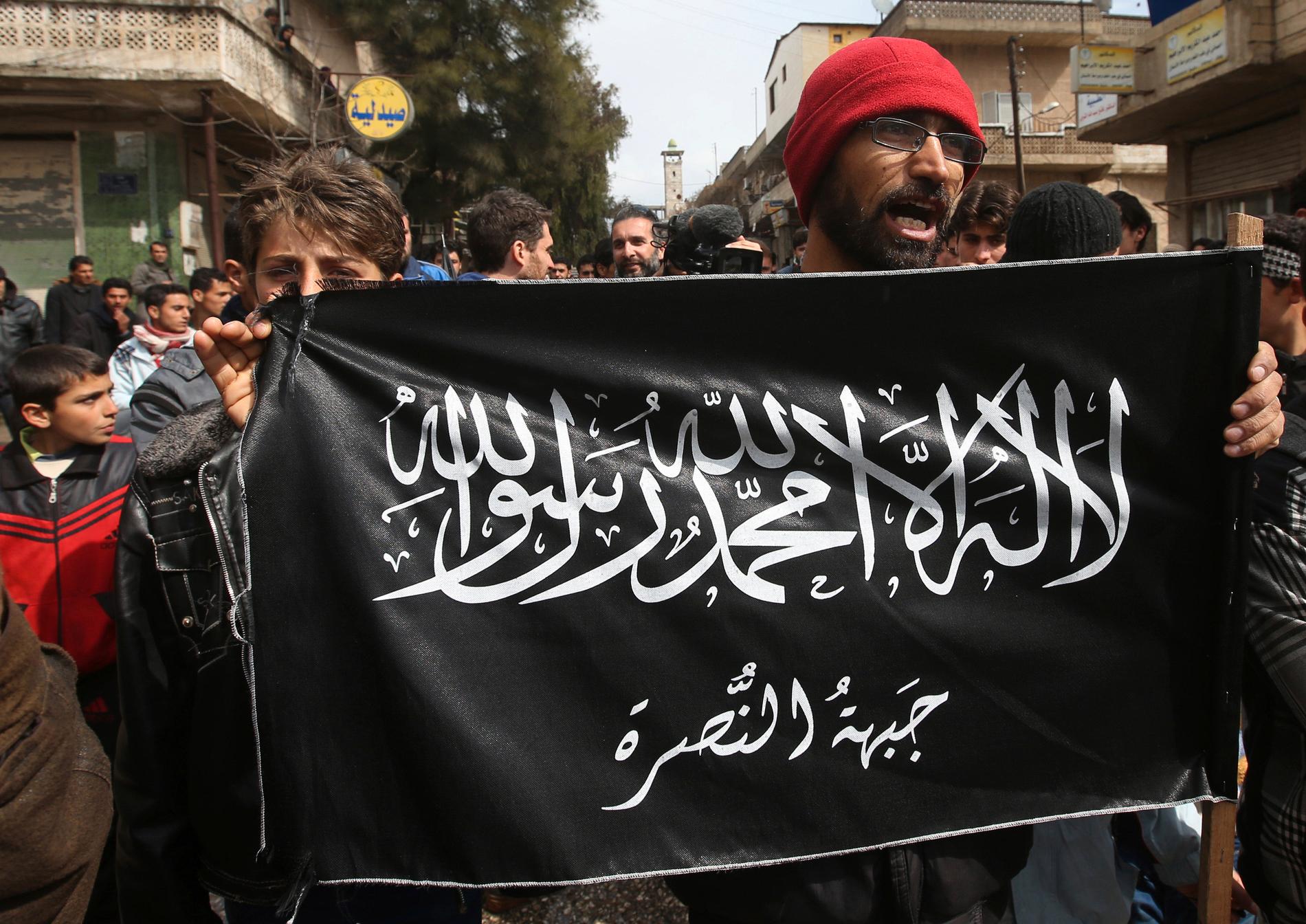 Demonstranter mot den syriska regimen håller upp terrorgruppen Jabhat al-Nusras flagga. Arkivbild