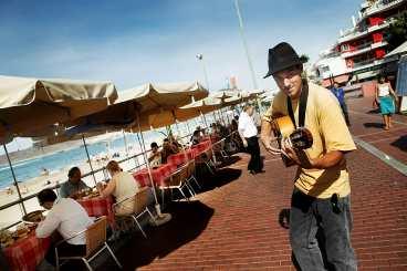Strandpromenaden Las Canteras kantas av flera uteserveringar. En man med gitarr underhåller flanörer och lunchgäster.