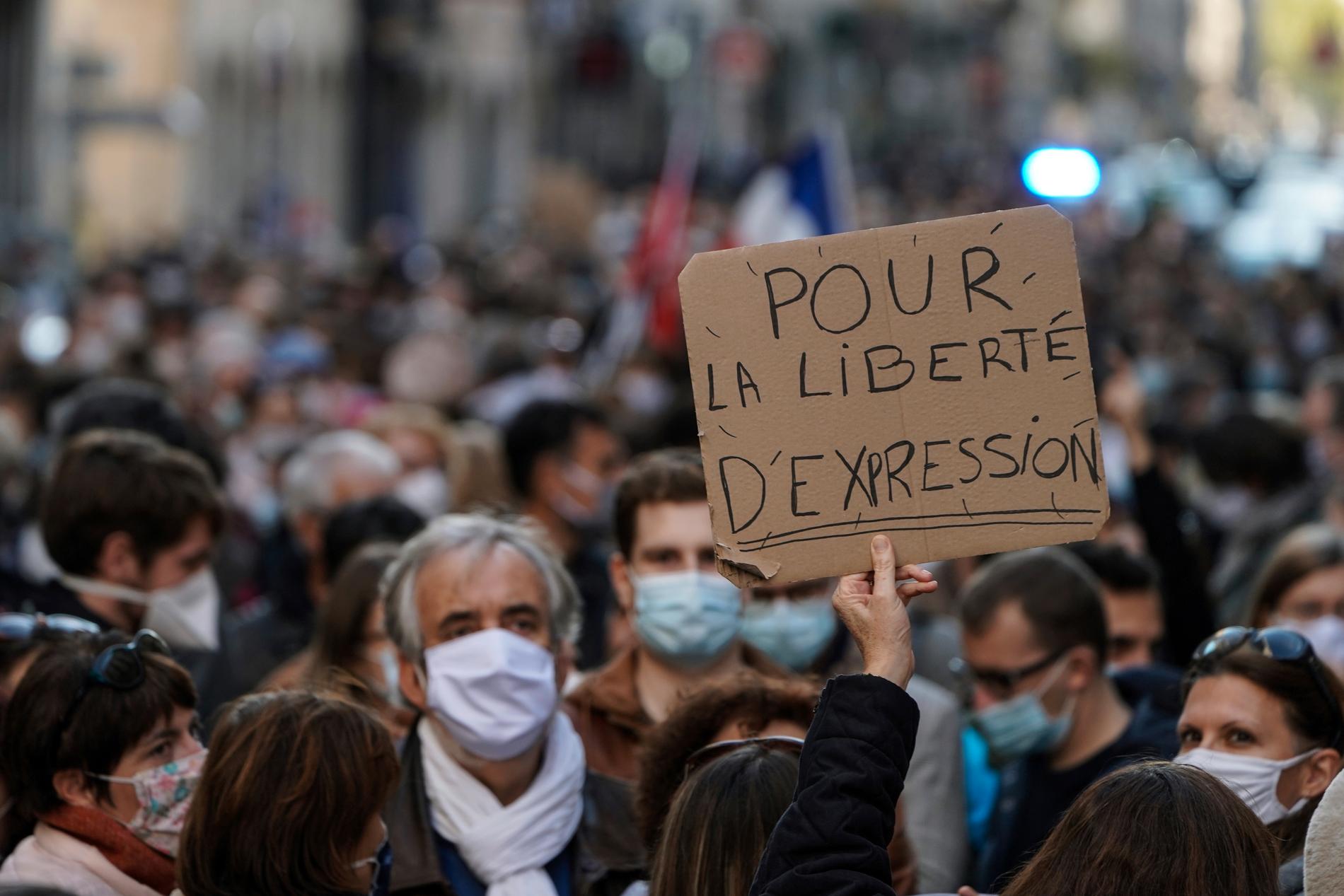 En man håller upp ett plakat med texten "För yttrandefrihet" vid en demonstration till stöd för den mördade läraren Samuel Paty, i Lyon.
