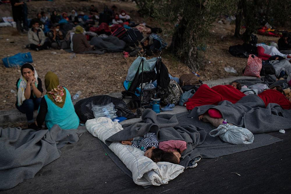 Flyktingar sover på marken efter jättebranden i lägret Moria.