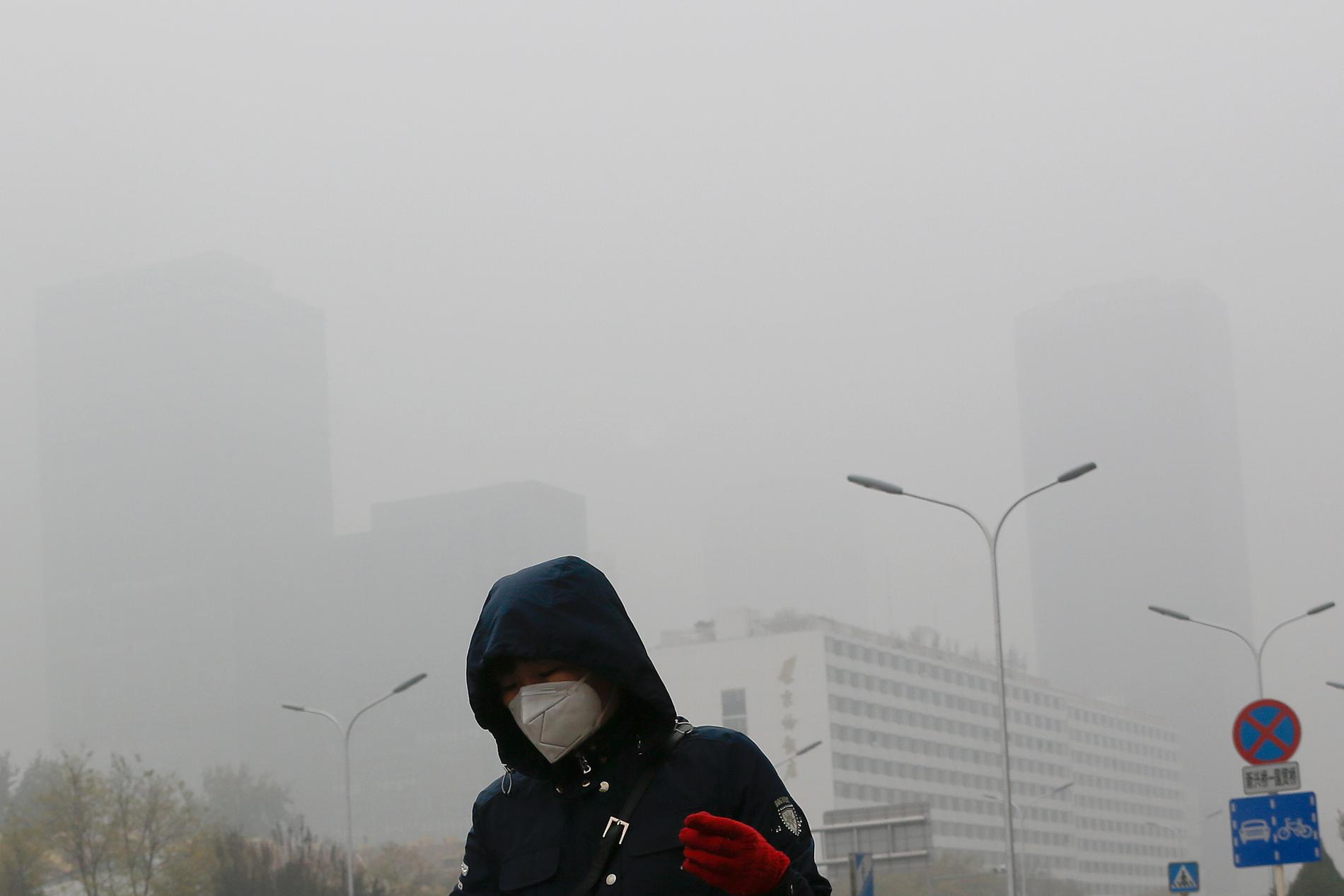 Tiotusentals människor beräknas ha dött i år till följd av luftföroreningar i Peking och Shanghai. På bilden bär en kvinna ett andningsskydd i ett smogtätt Peking. Arkivbild från 2018.