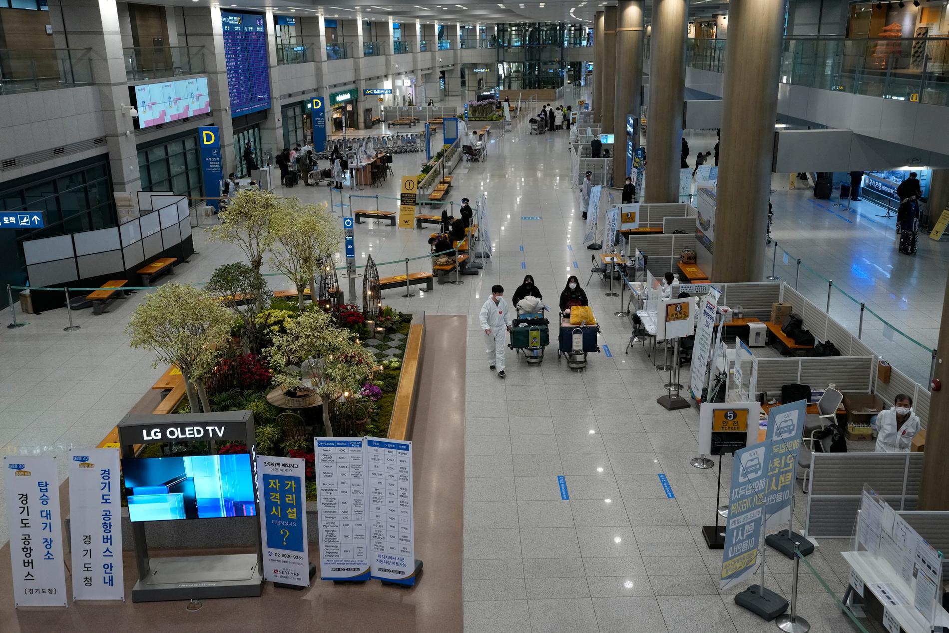 Två passagerare lotsas rätt av karantänpersonal vid flygplatsen Incheon i Sydkorea.