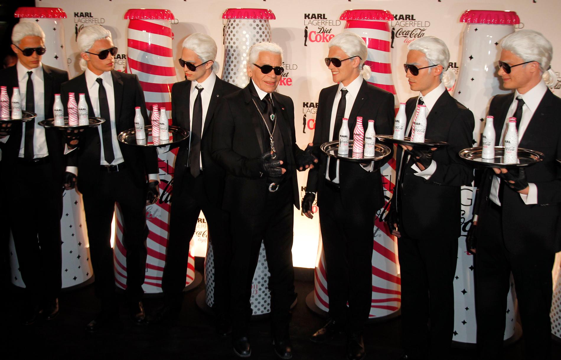 Karl Lagerfeld poserar med servitörer klädda som honom under ett evenemang med Coca Cola-flaskor som han designat. 2011
