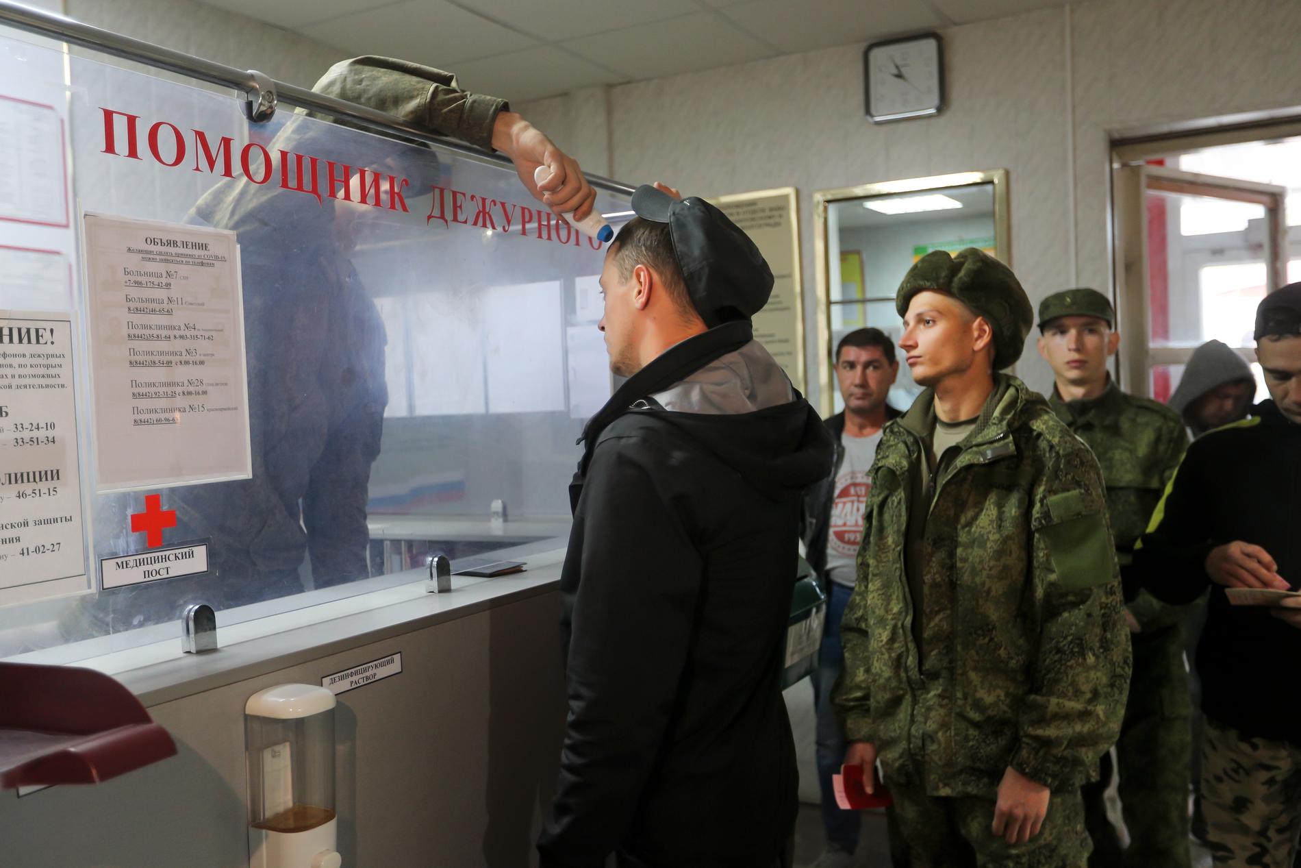 En man får sin temperatur mätt i kön till att bli registrerad som rekryt. Bilden från Volgograd den 24 september.