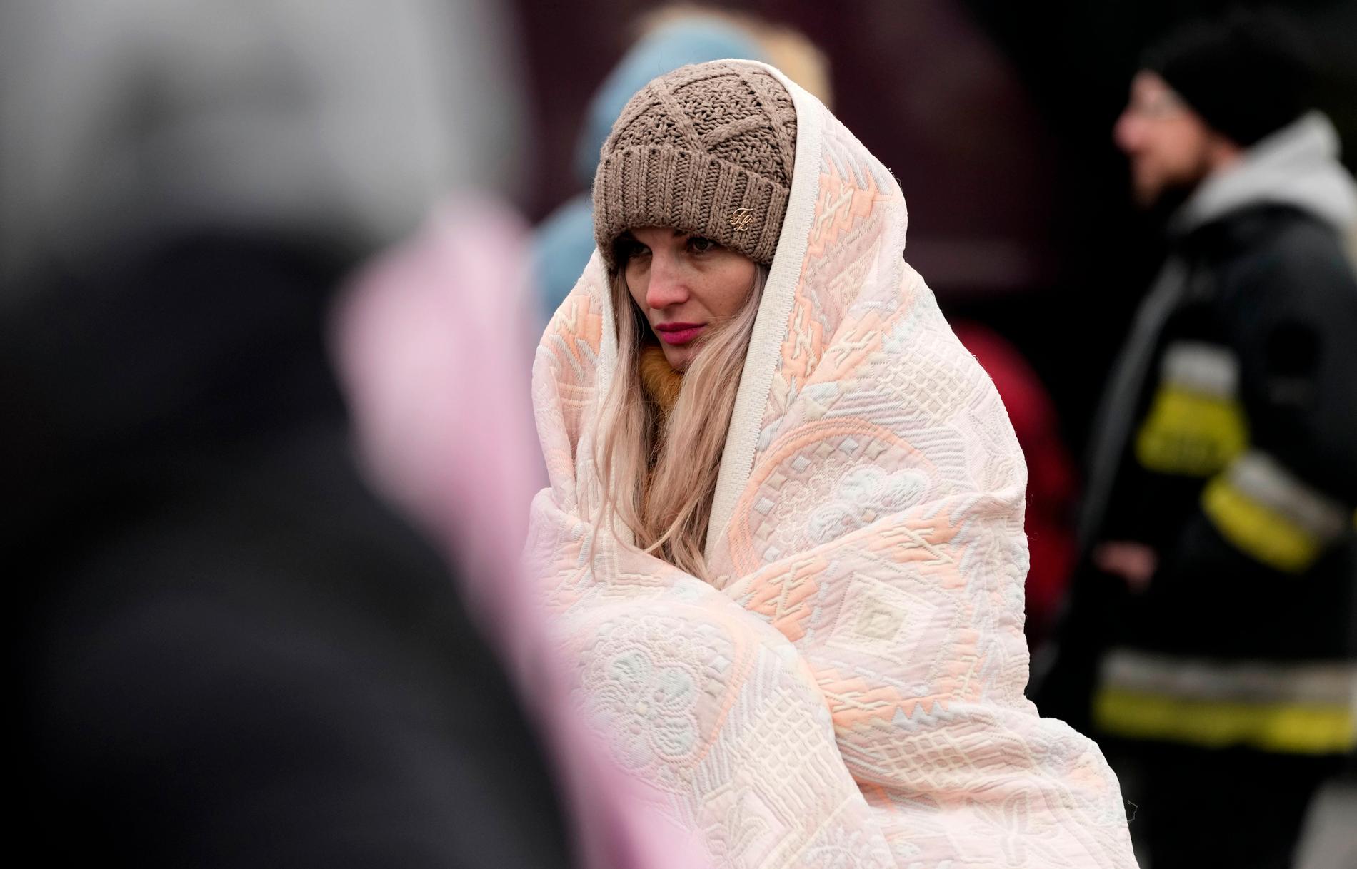 En kvinna som flytt Ukraina håller sig varm med en filt  efter att ha kommit över till polska sidan vid Przemysl. 