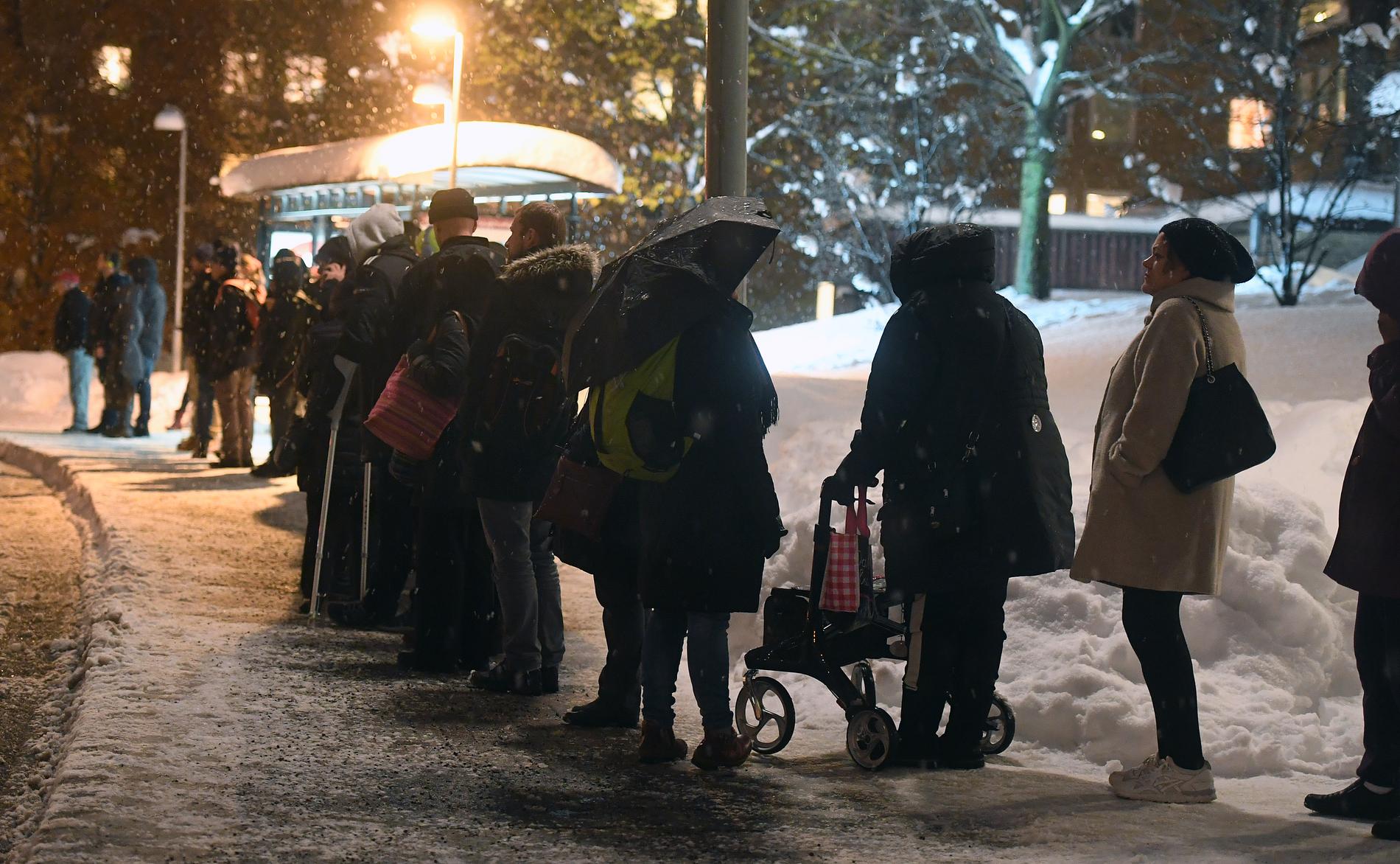 Arkivbild. Människor köar till försenade bussar i snöoväder.
