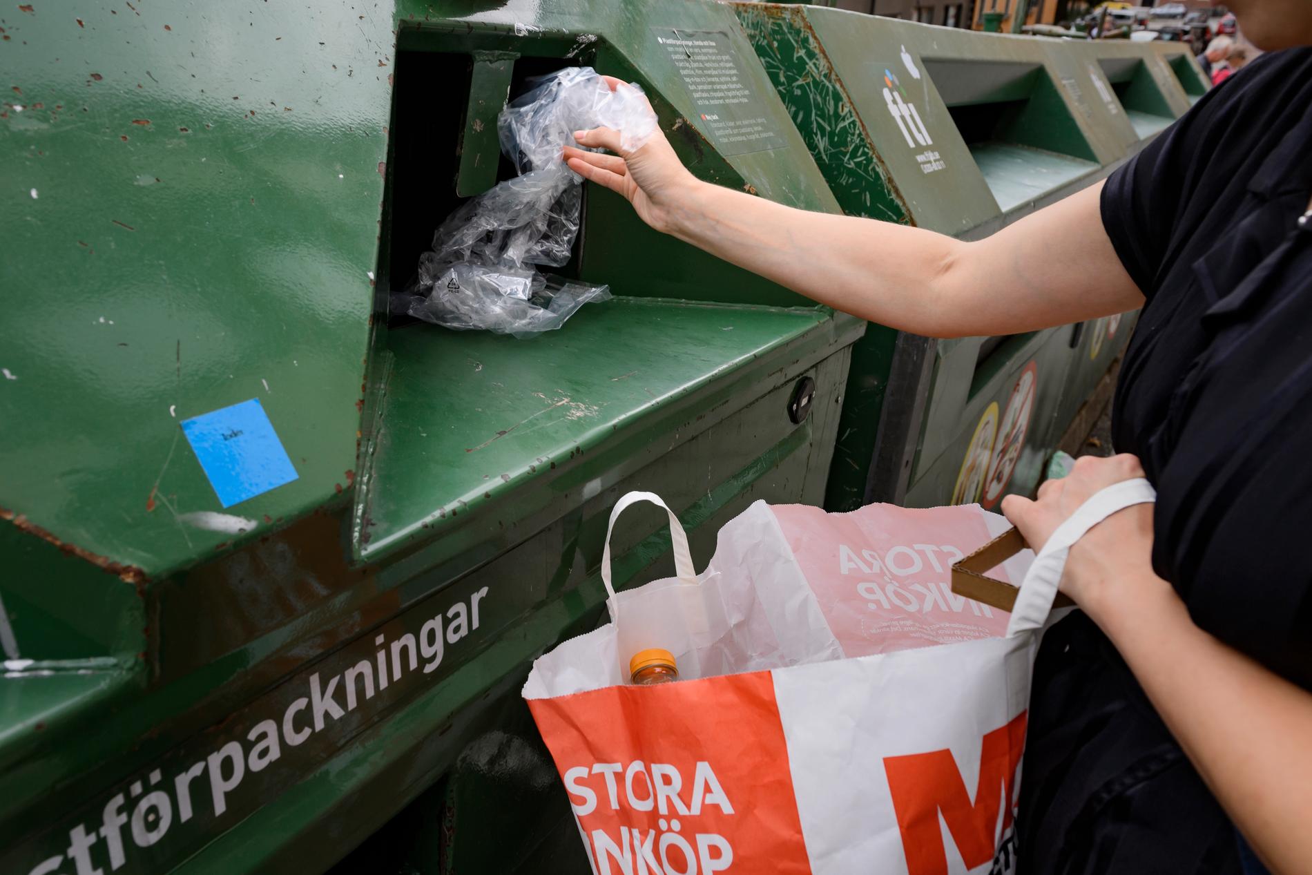 En kvinna lämnar plast i en återvinningscontainer.